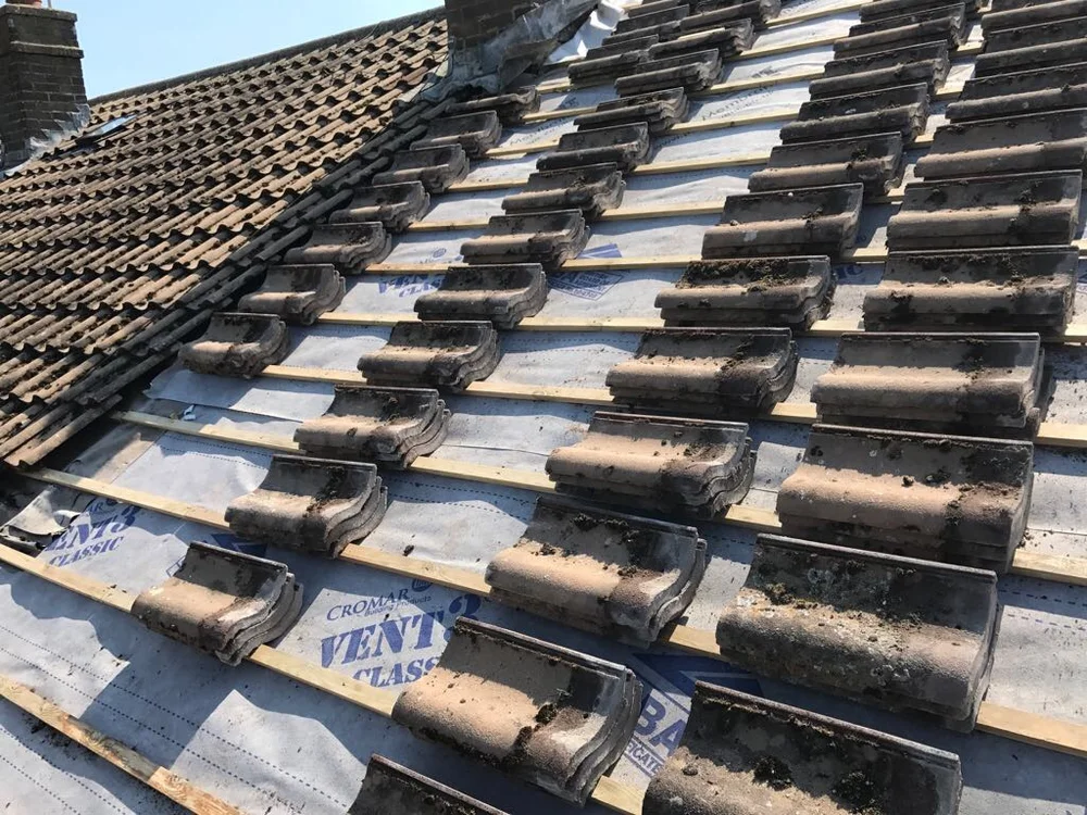 Existing roof tiles being relaid over renewed membrane and battens