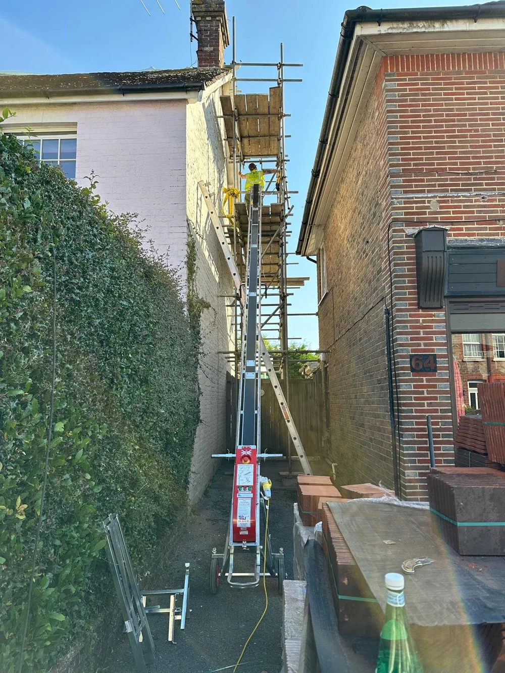Bespoke scaffolding and material hoist arranged for chimney-level access