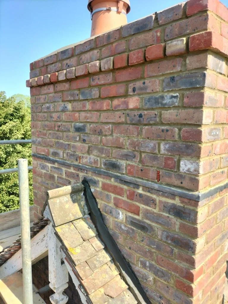 Renewed brick chimney masonry on a pitched roof