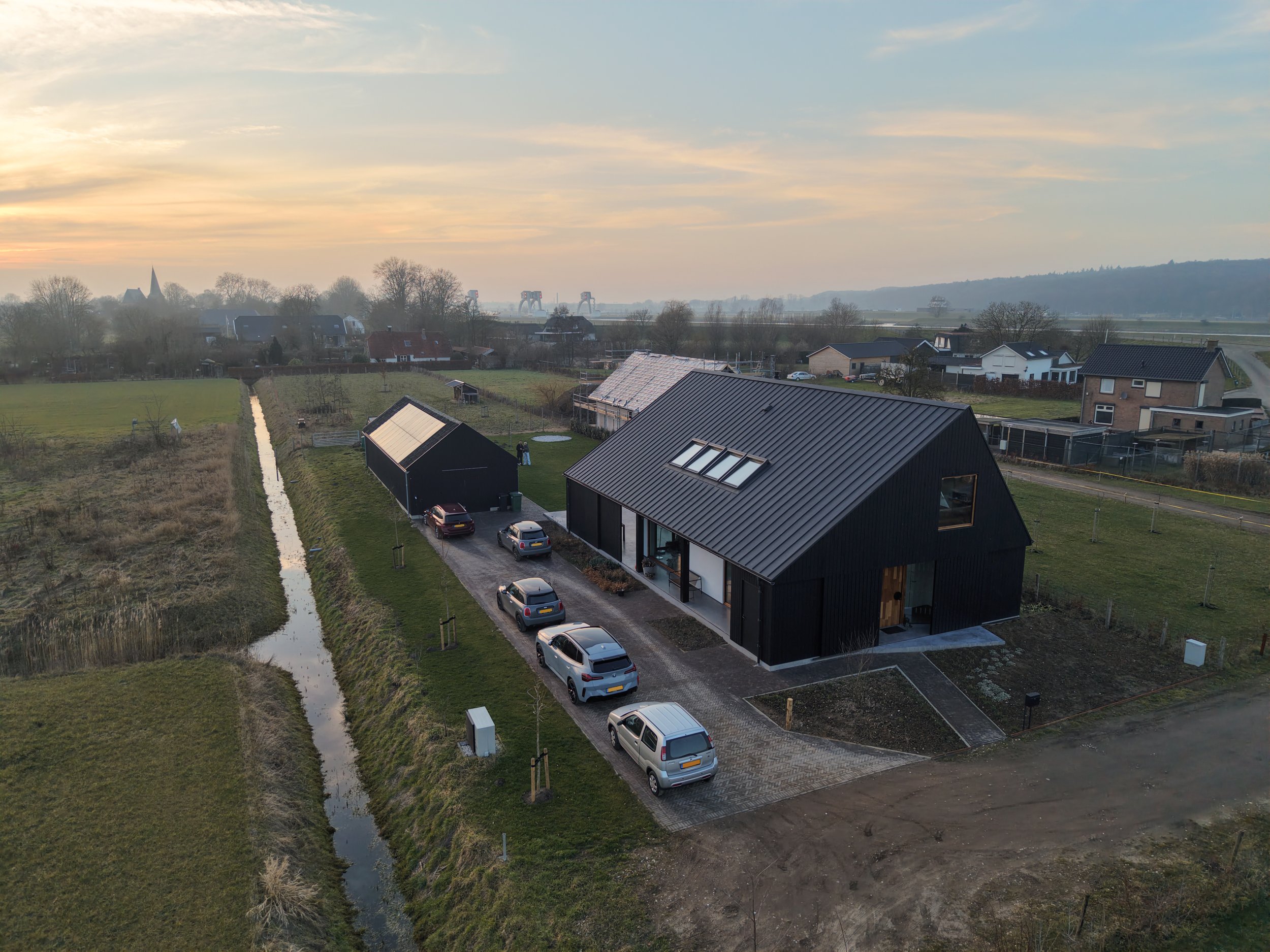 Schuurwoning met zwarte houten gevel en zinken dak. Landelijke setting op voormalig boerenerf met uitzicht op de rivier de Rijn, Driel en de Drielse Rijndijk.