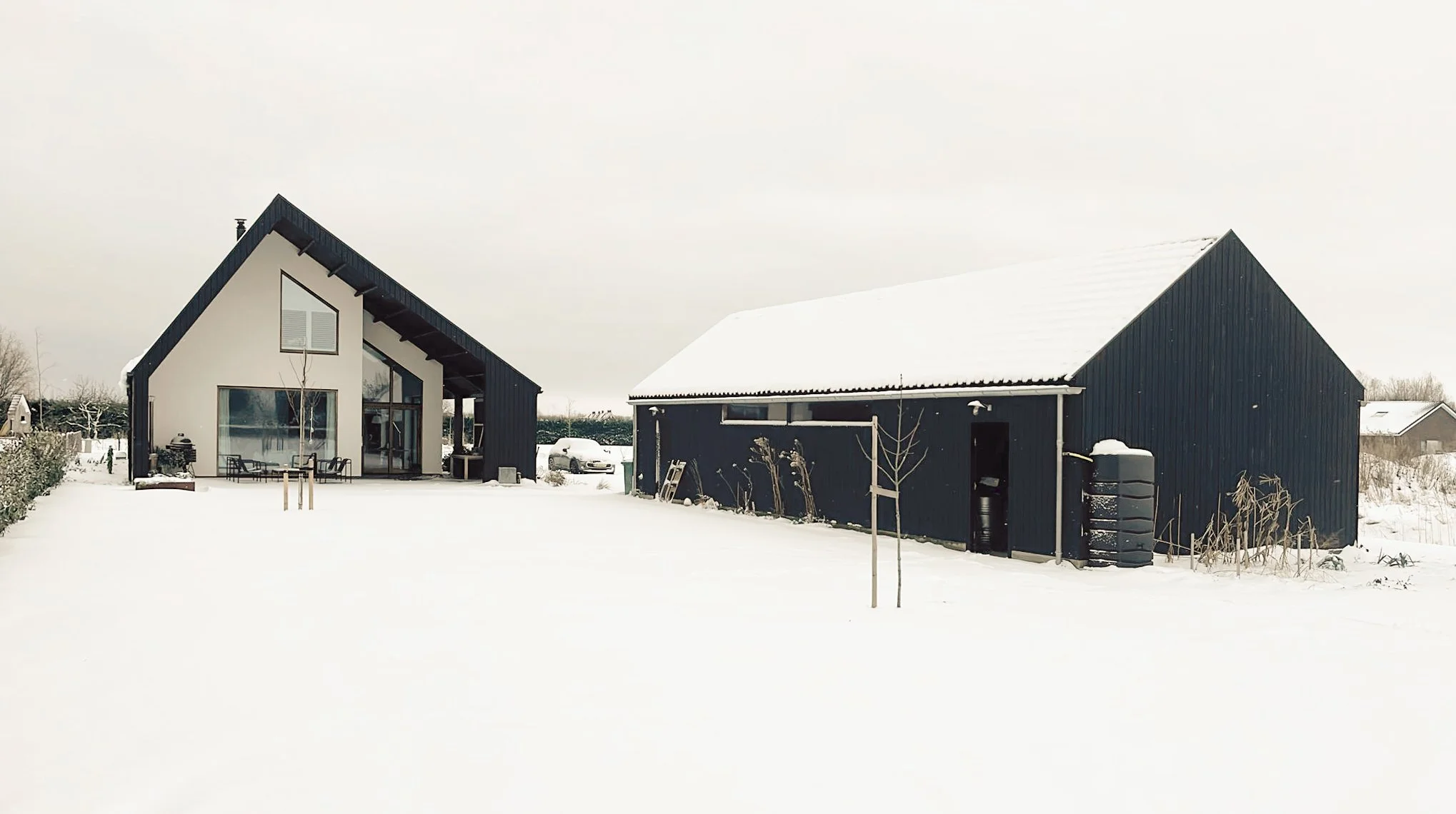 Achtergevel moderne schuurwoning met grote overkapping in de sneeuw.