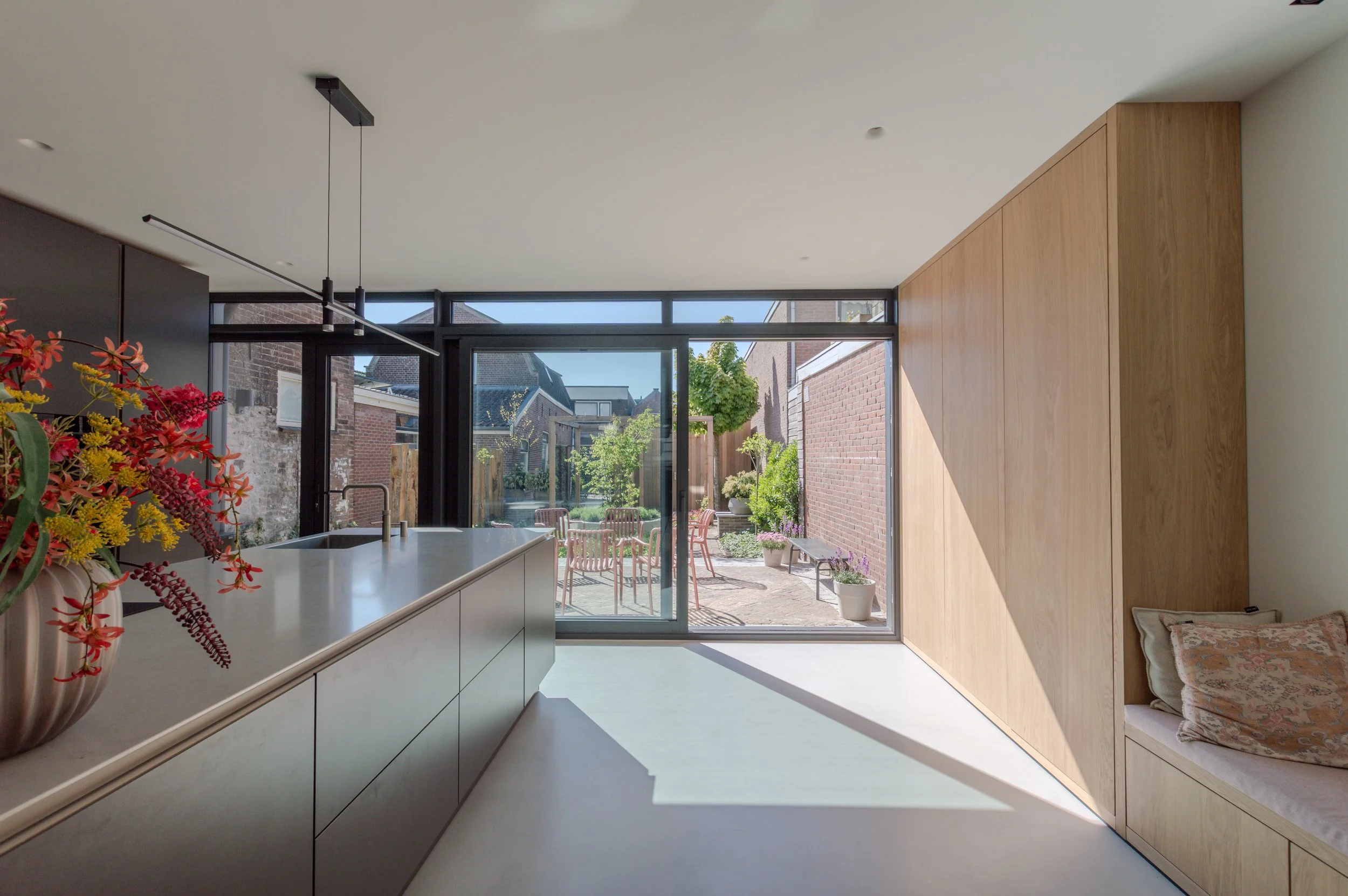 modern kookeiland met zicht op binnentuin. houten wandmeubel met lounge zitje.