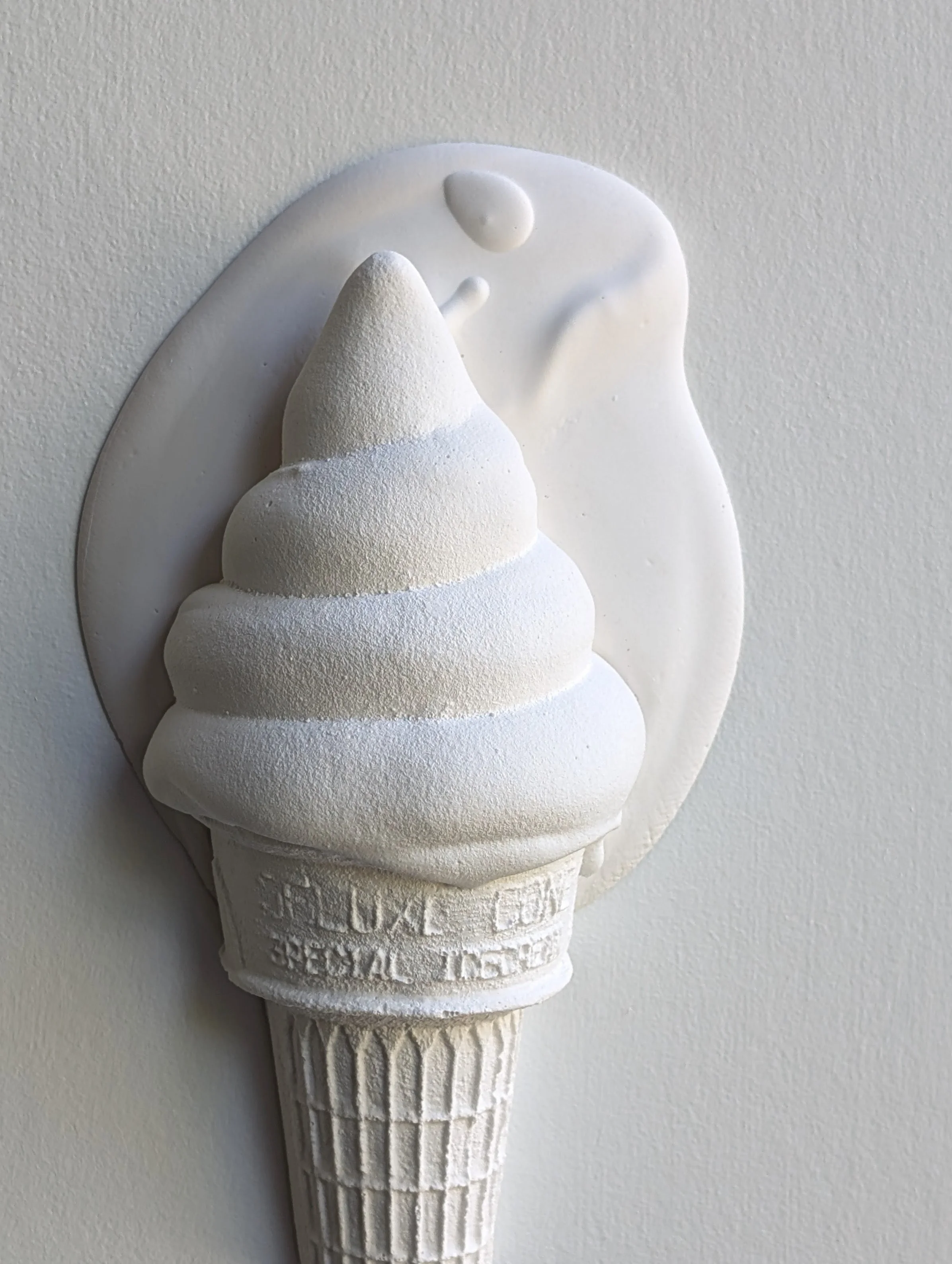 Monochromatic high-contrast all-white wall sculpture of ice cream.