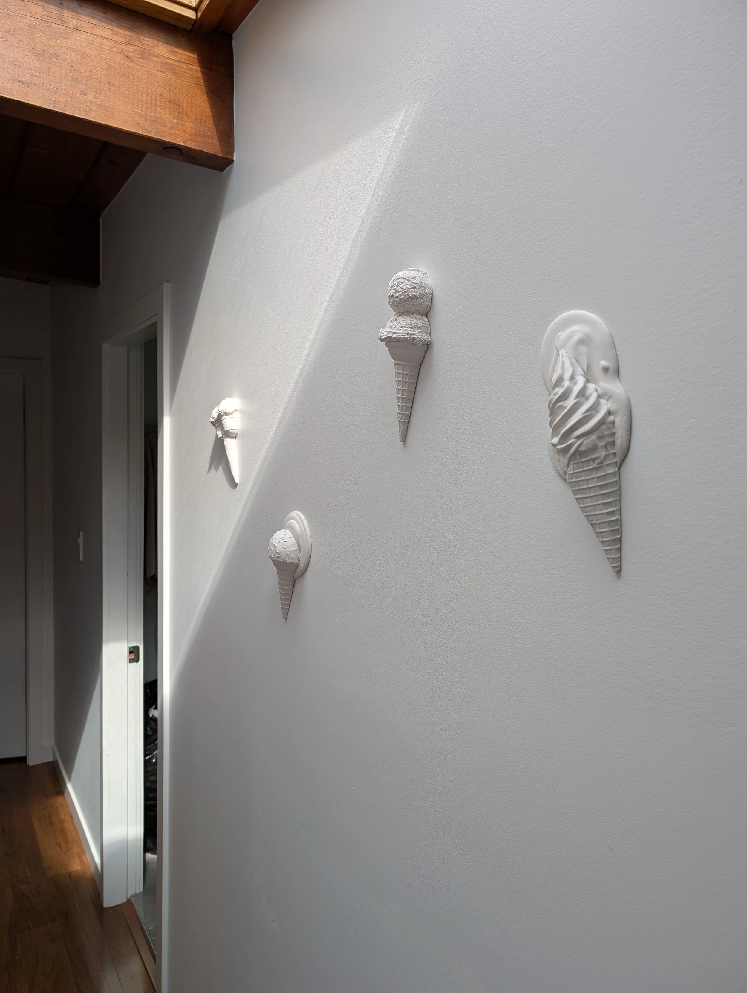 White minimalist ice cream cone sculptural artwork arranged on a white wall in a wabi-sabi pattern in Vancouver, BC