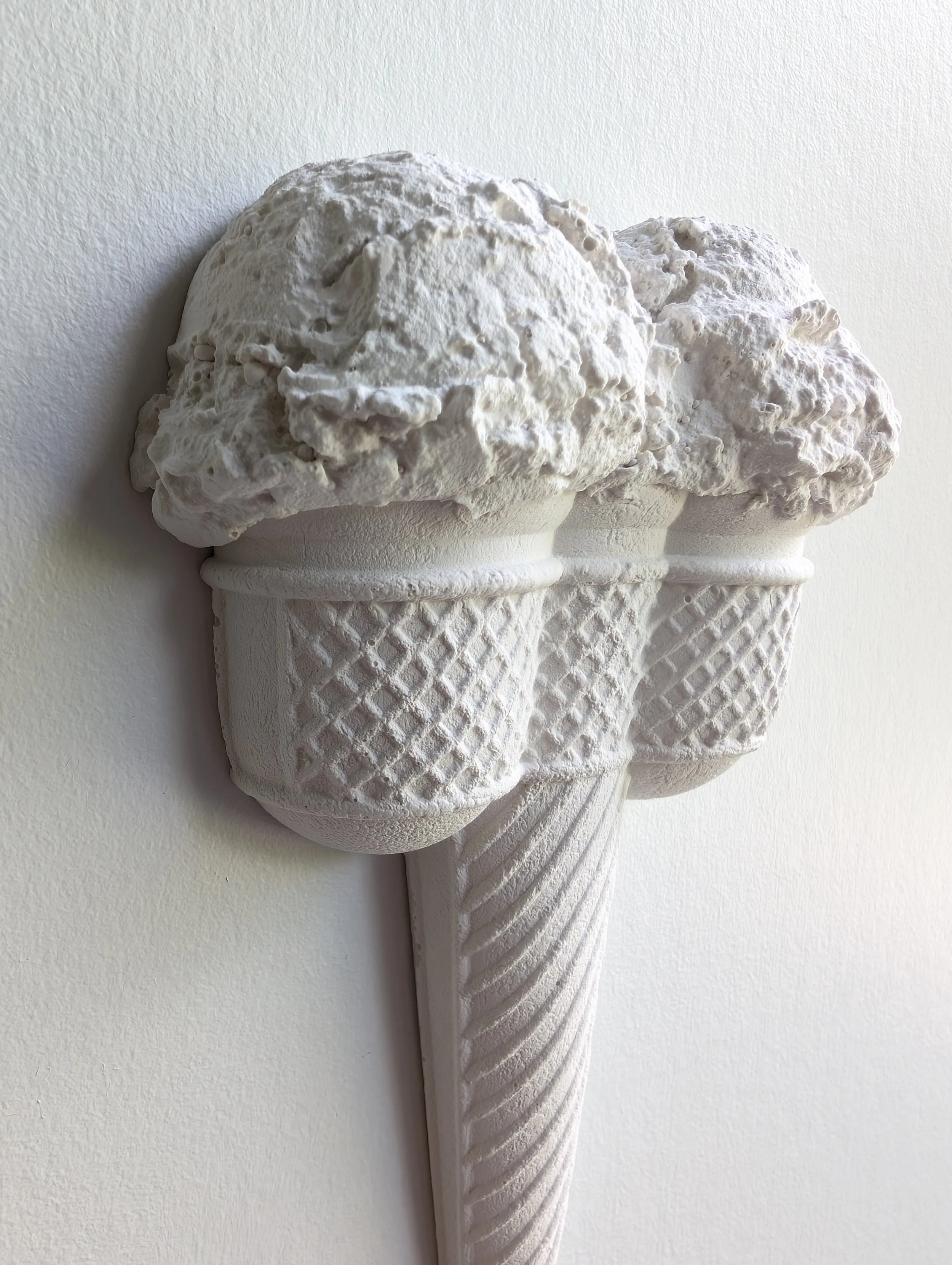 Deep sculptural ridges, highlights, and shadows on a close-up view of a matte white ice cream sculpture. Artwork created in Vancouver by Canadian artist Lindsay Cohen