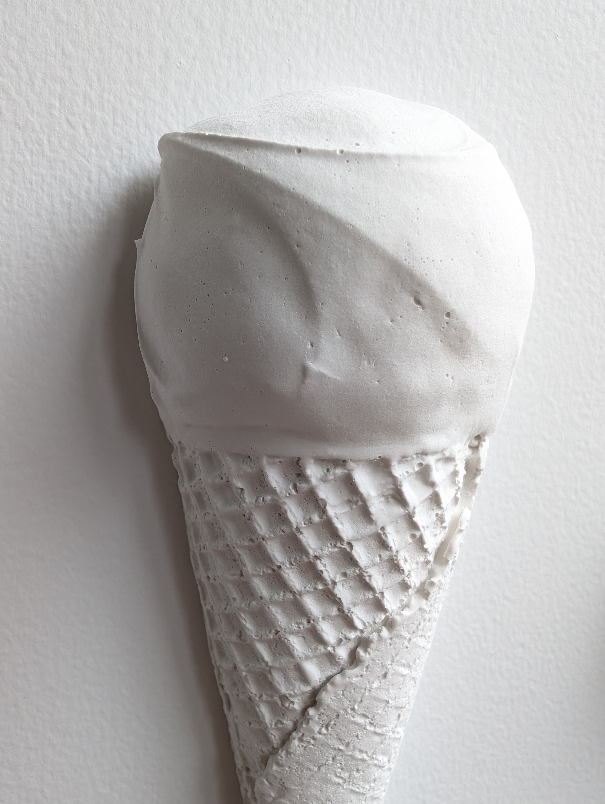 Details, highlights, and shadows of an all-white sculptural wall-mounted artwork. Ice Cream sculpture created by artist Lindsay Cohen.