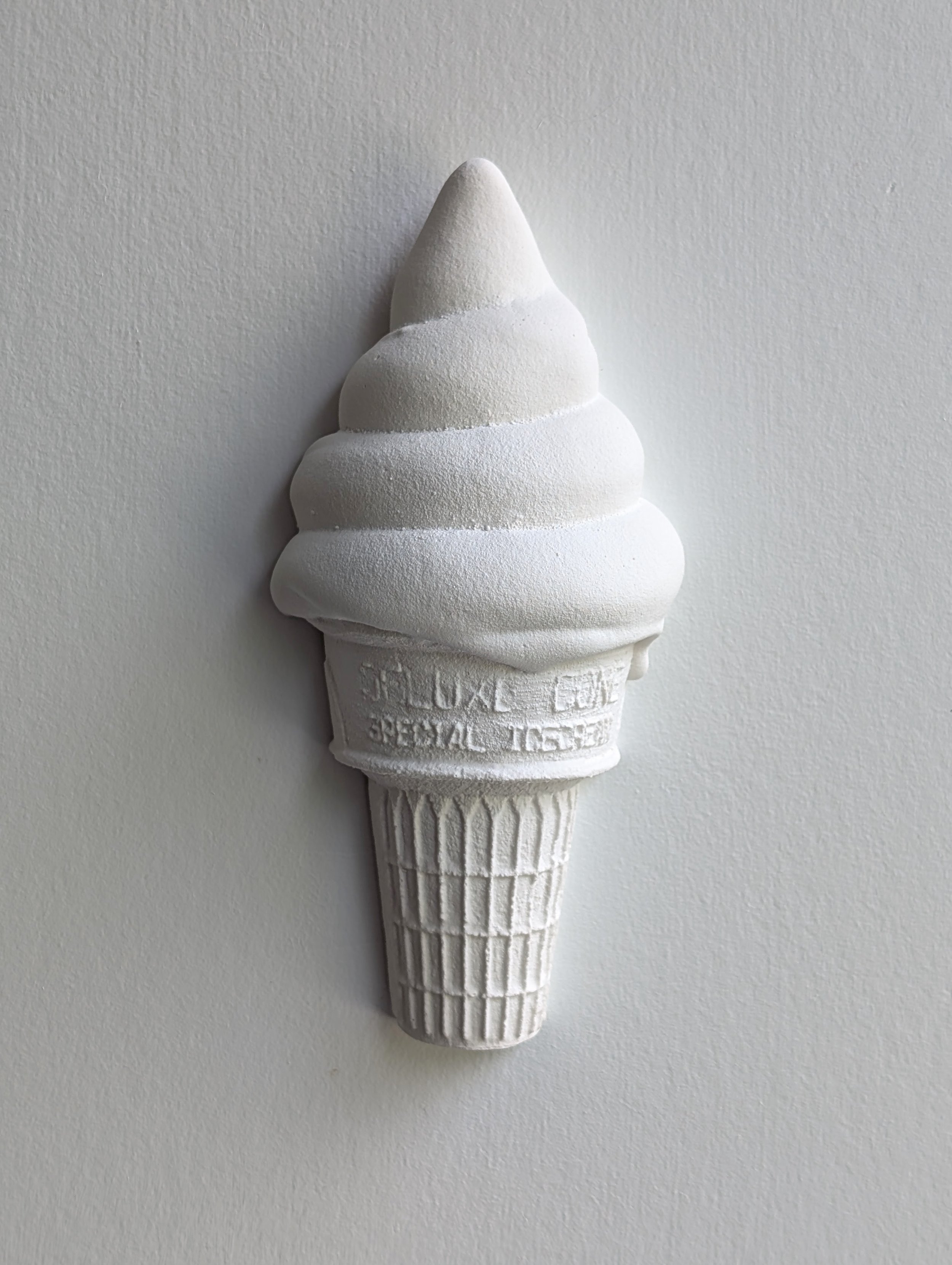 Wall-mounted minimalist white sculpture of an ice cream created by Vancouver artist Lindsay Cohen.