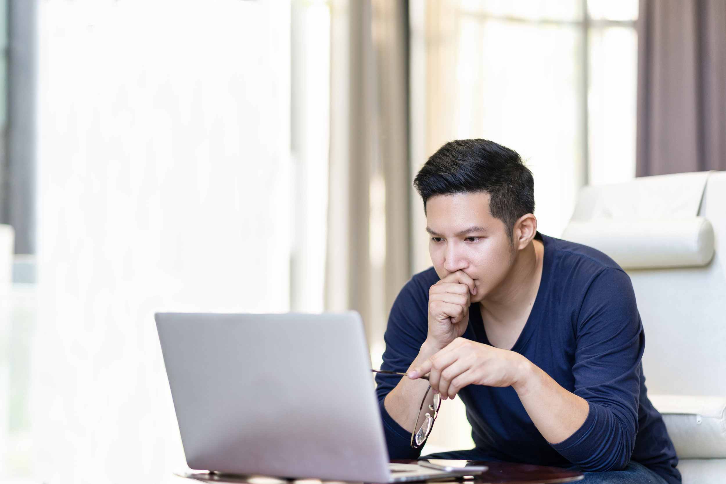 seriously-confident-asian-young-freelancer-in-smart-casual-working-and-concentrated-on-laptop-sitting-on-desk-in-modern-office-,co-working-space-or-at-home-with-copy-space,-webinar-over-the-internet-941051088_3869x2579.jpeg