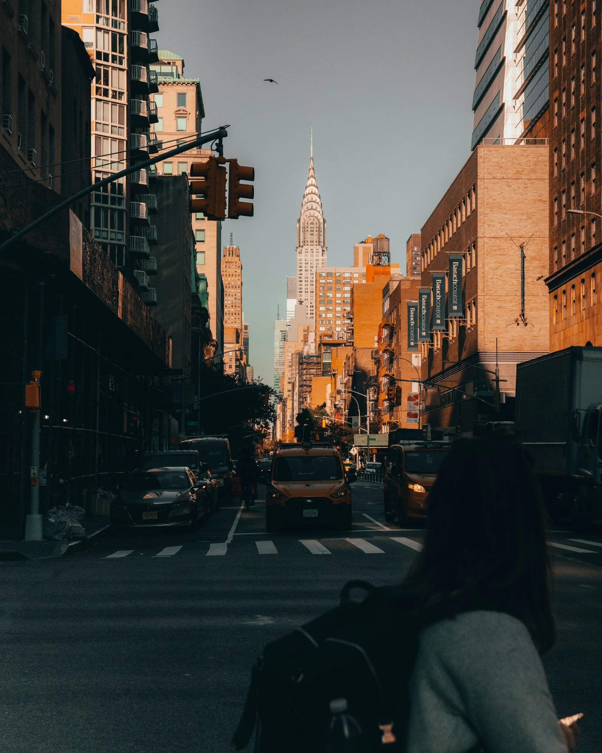 Woman crosses the street in NYC. Cars and skyscrapers are in the background