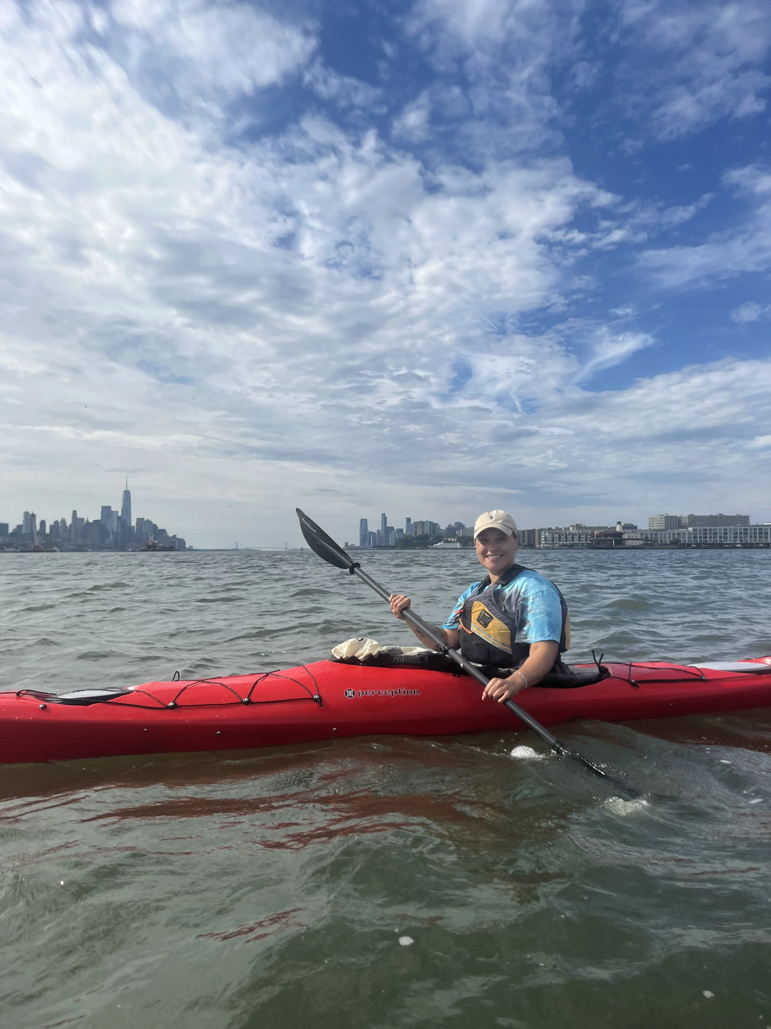 therapist Kiana Kohr is kayaking on the hudson with the NYC skyline behind her