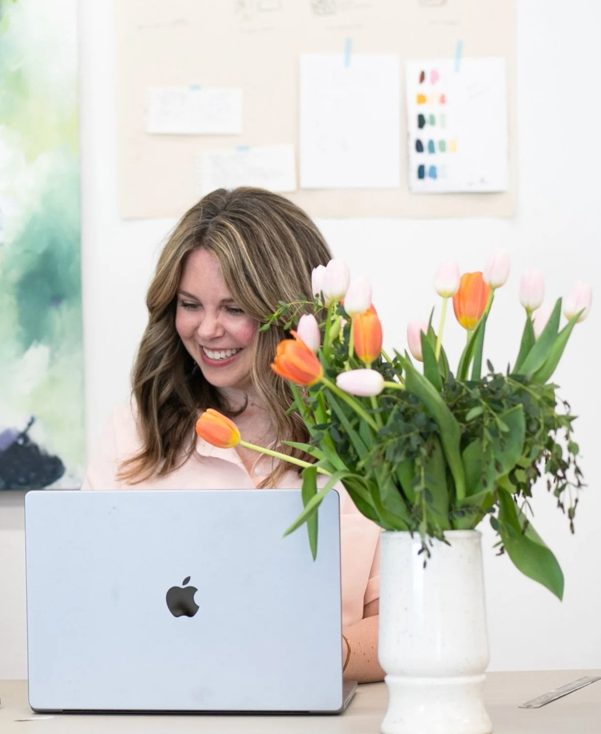 Nicole Bissett writing at a desk with spring tulips