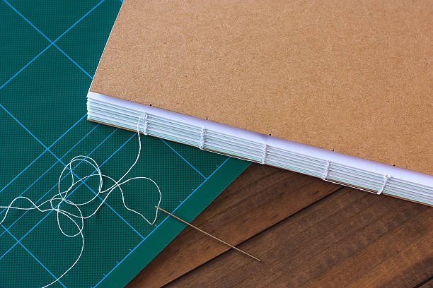  Handbound book with needle and thread on wooden background 