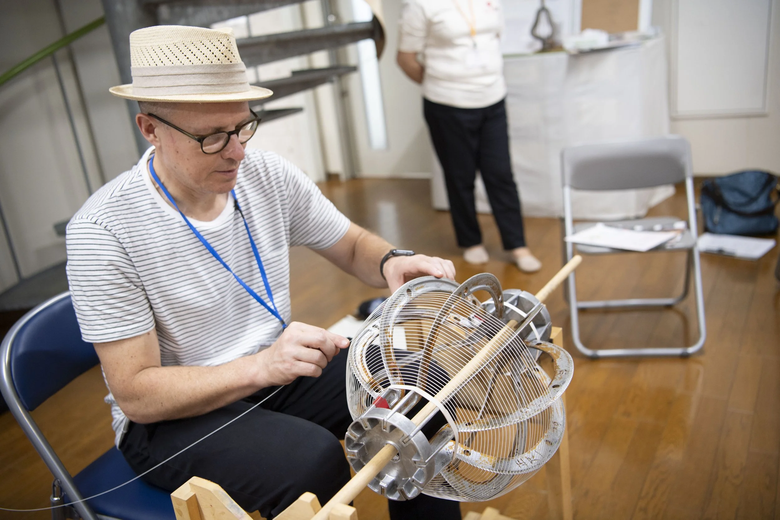  A white man spins a the tool that's used to paste a sheet of paper on a lantern 