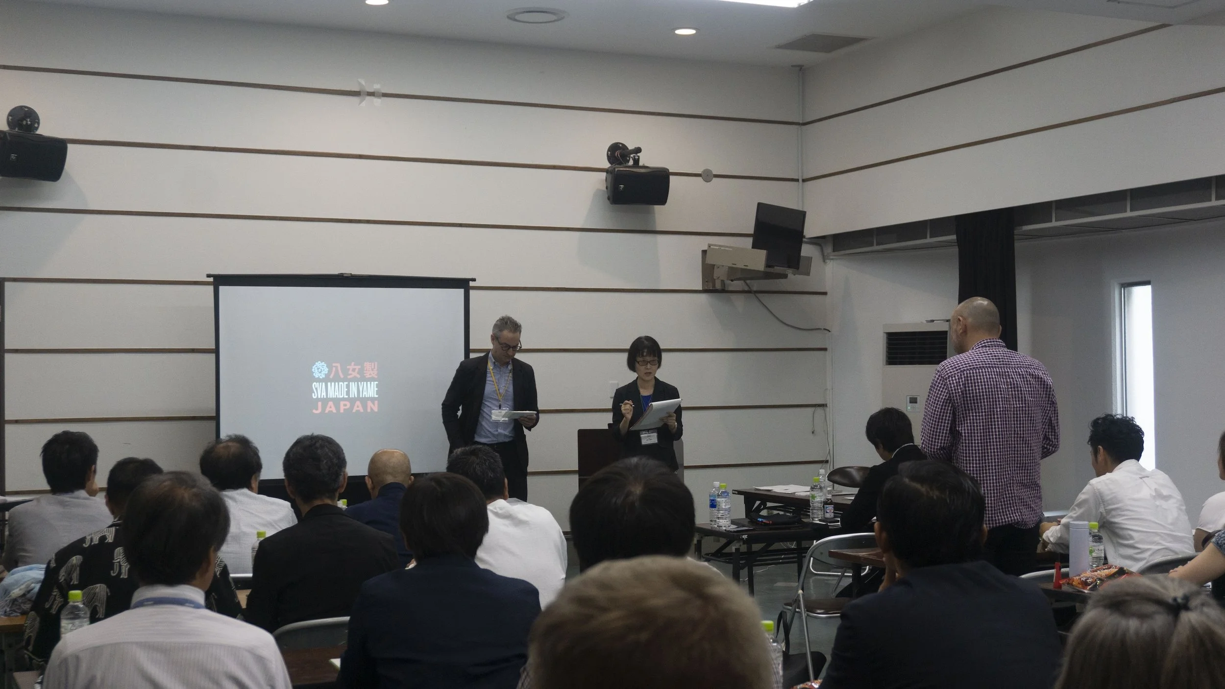  A man and a woman standing in front of a room full of an audience 