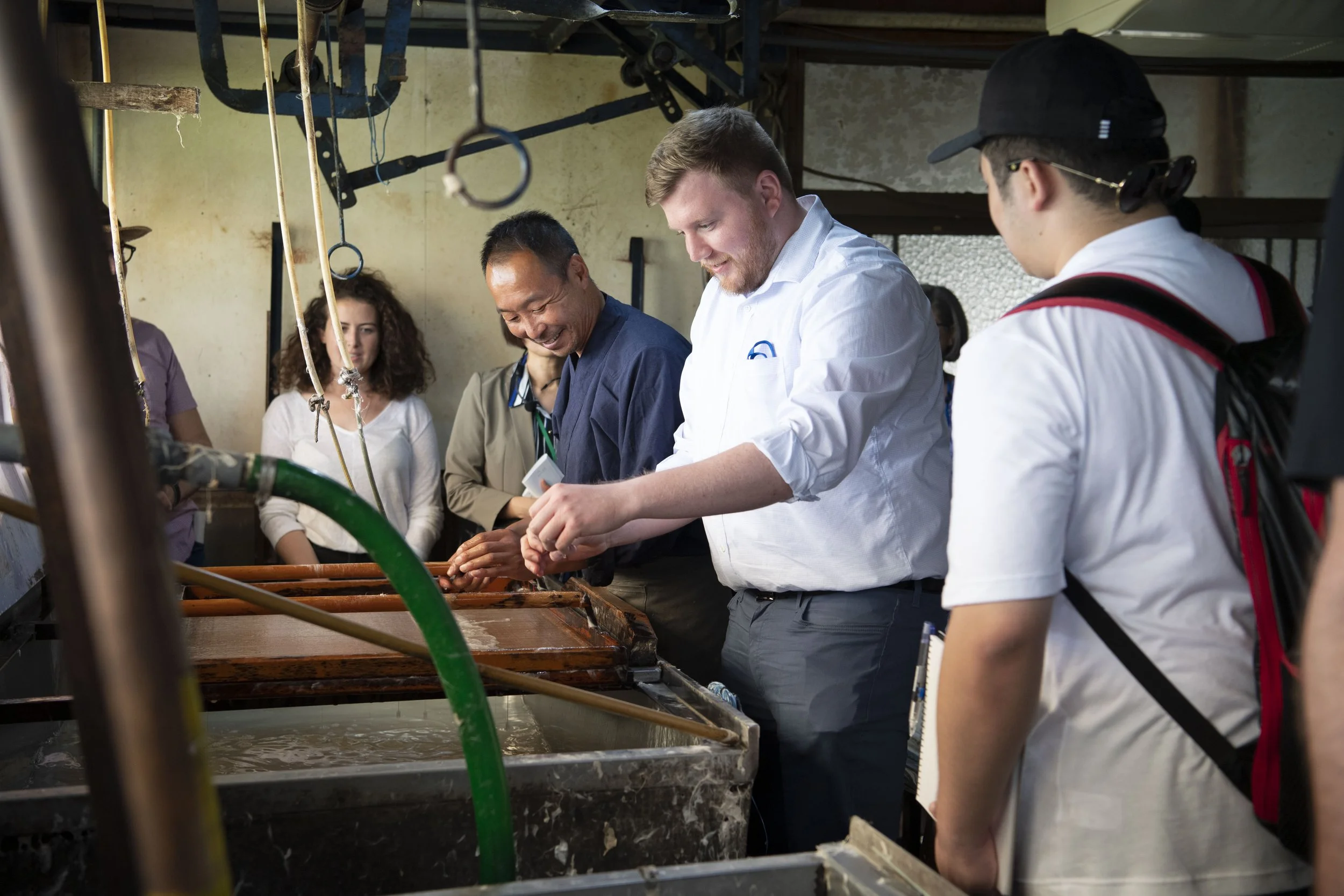  In the washi paper studio, a crafts person shows a man how to use his tools 