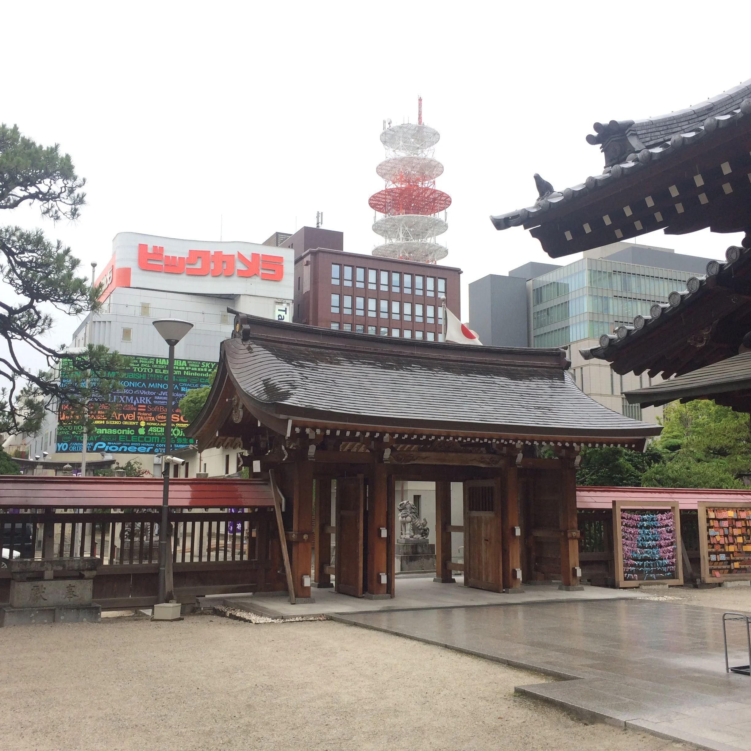  The gate of a traditional Japanese shrine with urban buildings in the background 