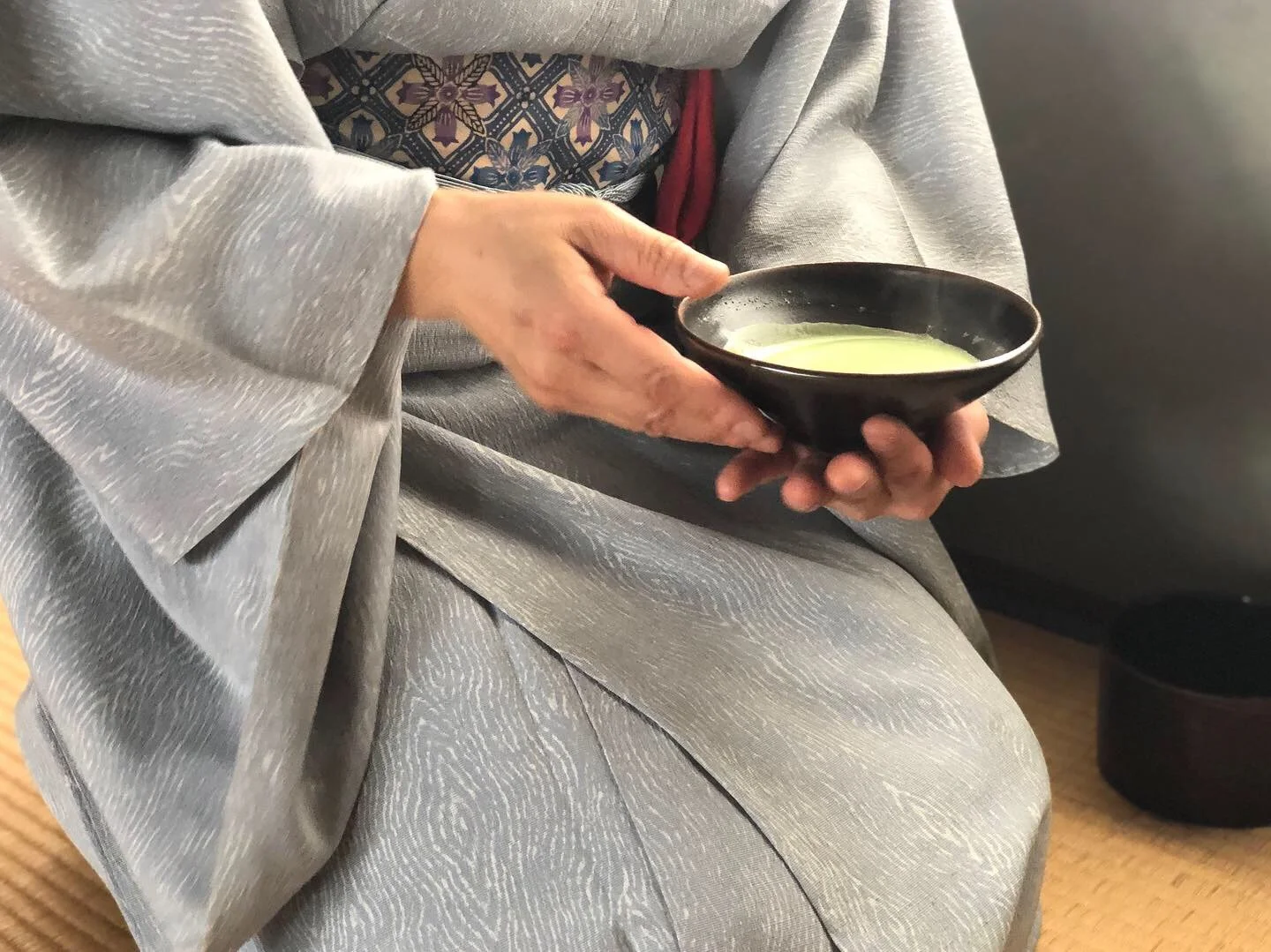  A close up of a woman in kimono holding a bowl of green tea 