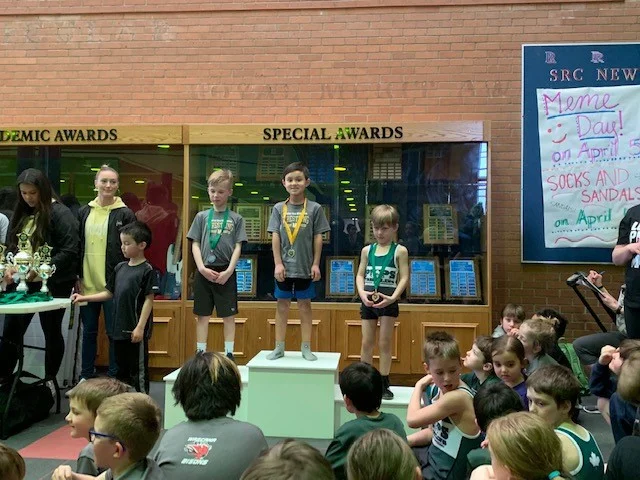 Charlie Bohn (left) and Riley Hill (center) Receive Their Medals