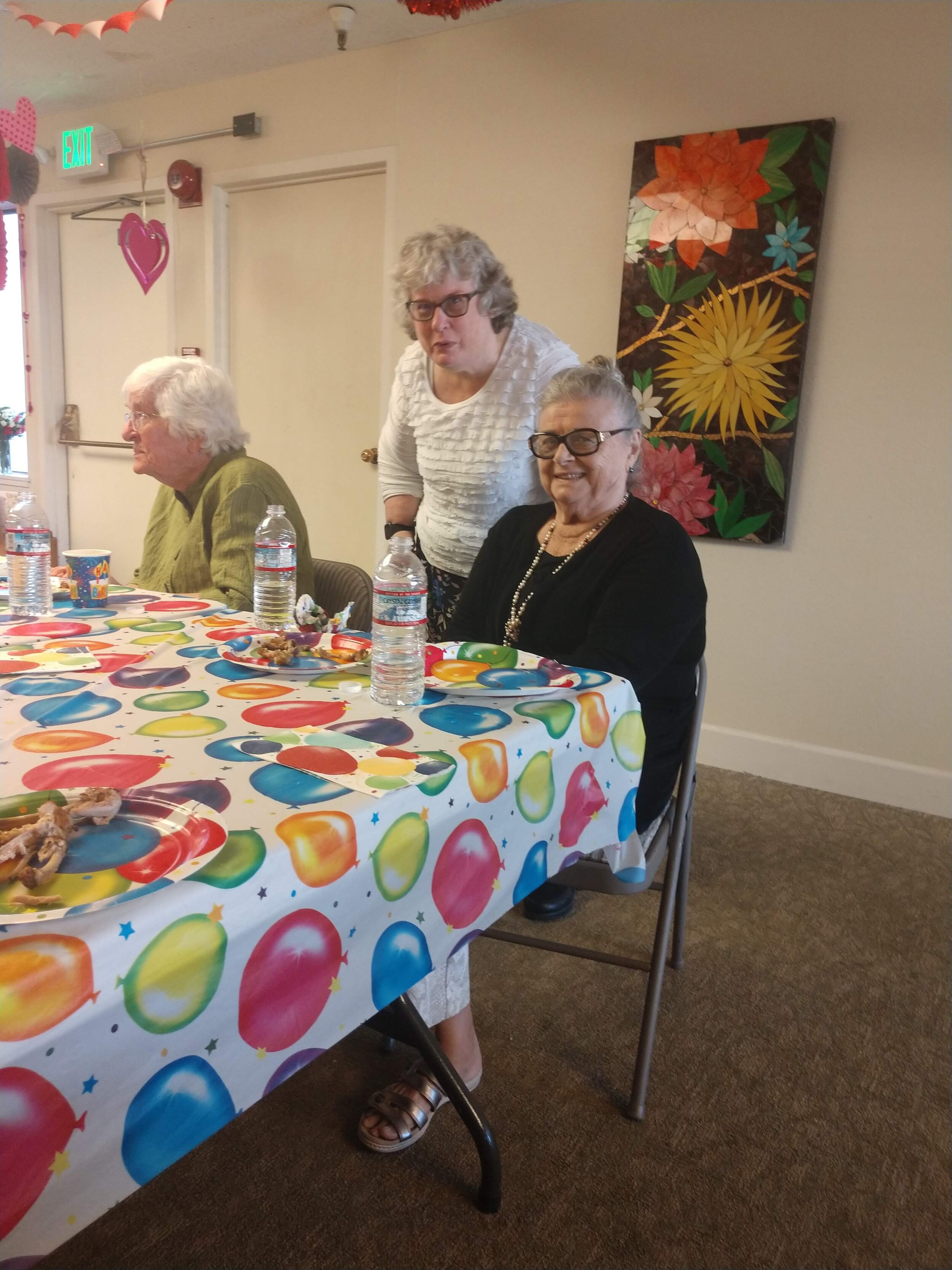 An image of the blog author at a birthday celebration standing in between two seated woman.