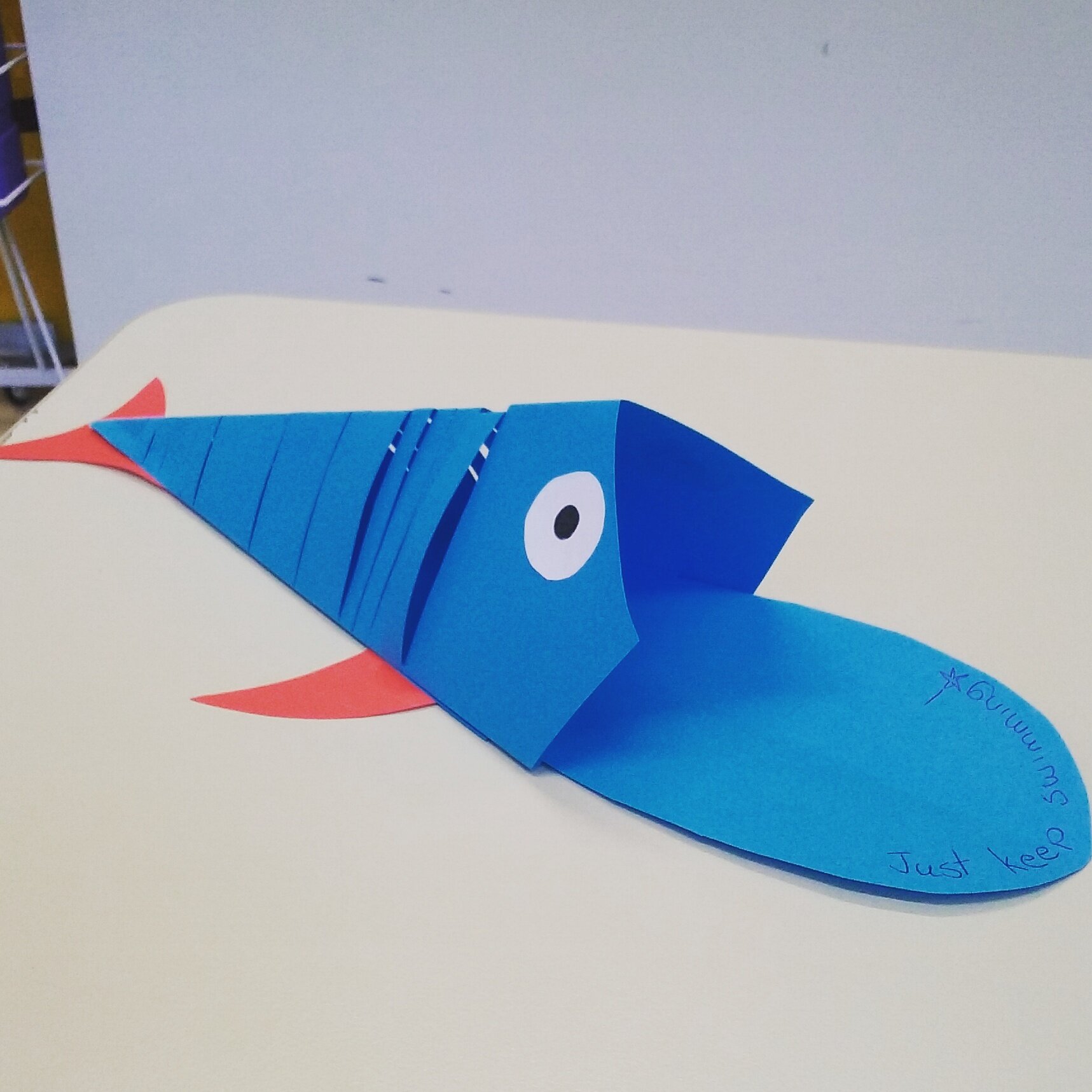 An image of a blue fish made from construction paper with the words, “Just Keep Swimming” written on its moth. Alyssa explains, “the fish was made by a kid who came to hospital with his mum. He made one for every person in the medical day unit.”