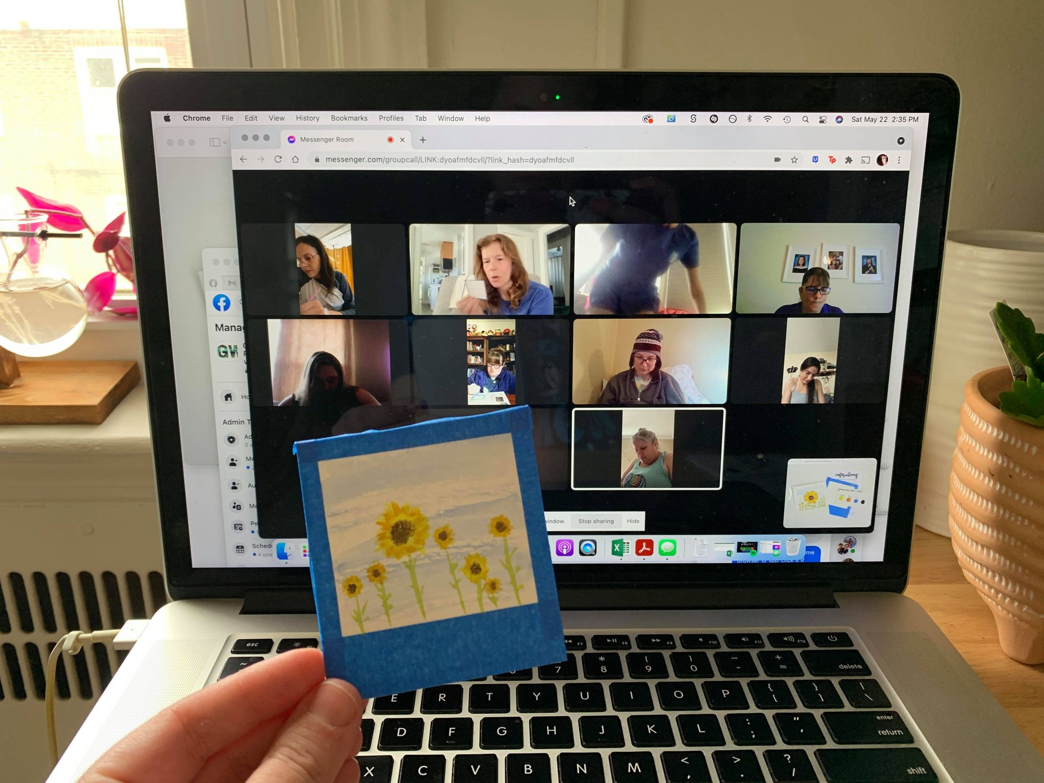 An image of painted sunflowers being held up to the computer screen as summit participants work on their crafts in the image background.