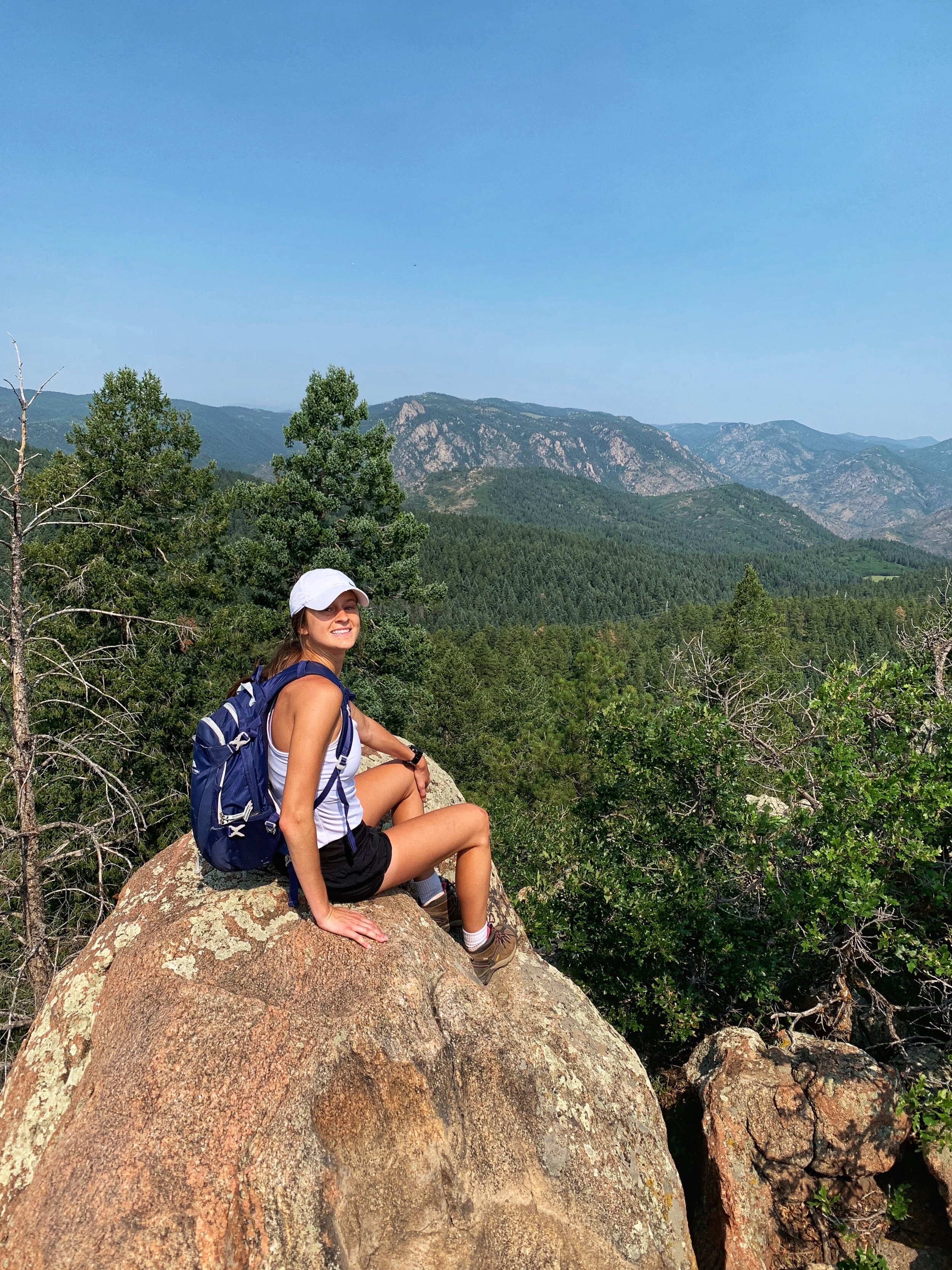 The blogger sits on top of a rock on the mountains.