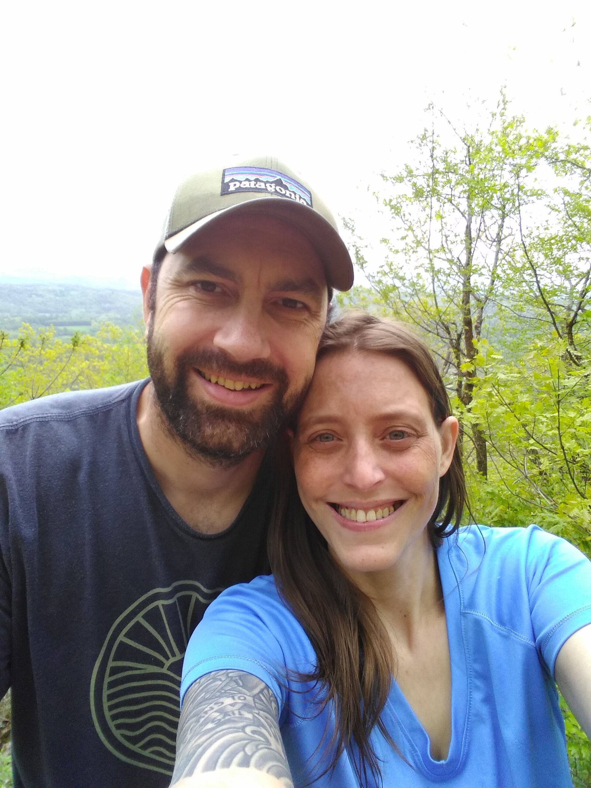 The blog author and her long-term hiking and adventure partner, Ryan outside, smiling, with trees and a mountain behind them.