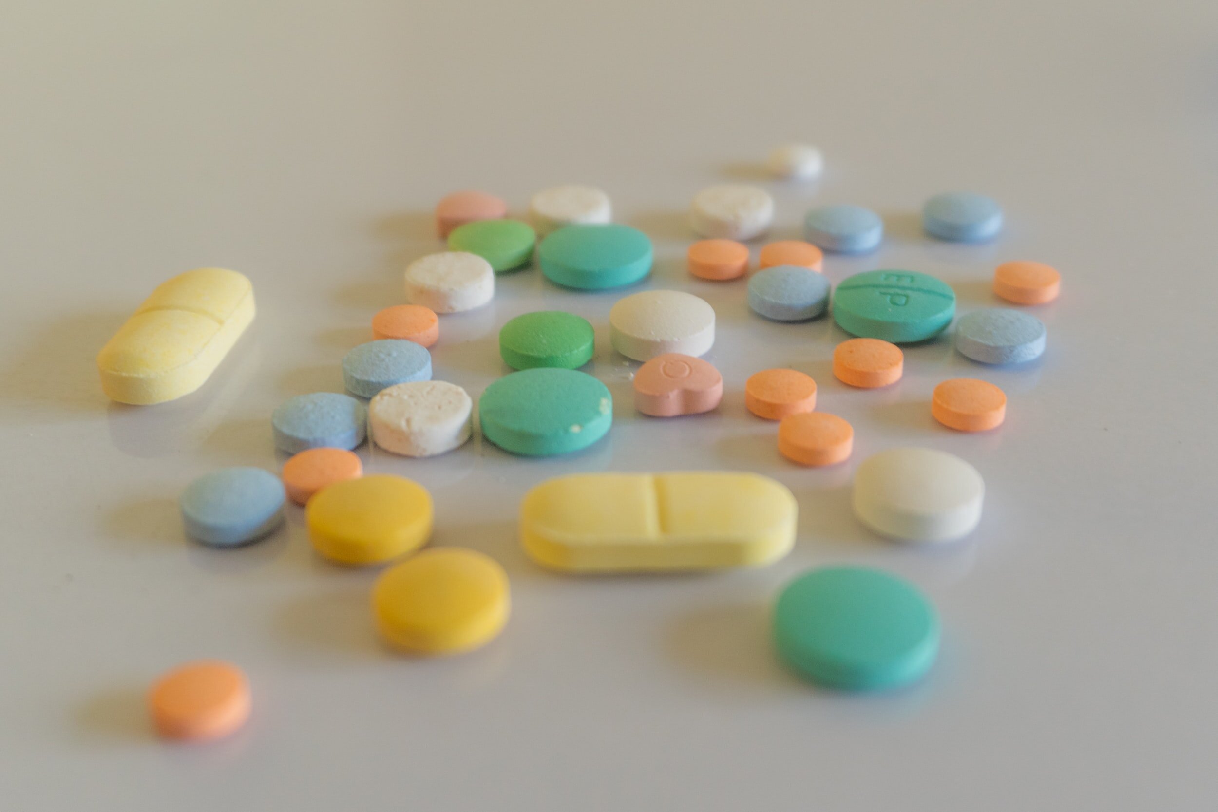 Photo by Prasesh on UnsplashAn assortment of pills ranging in shape and color sit on top of a white counter.