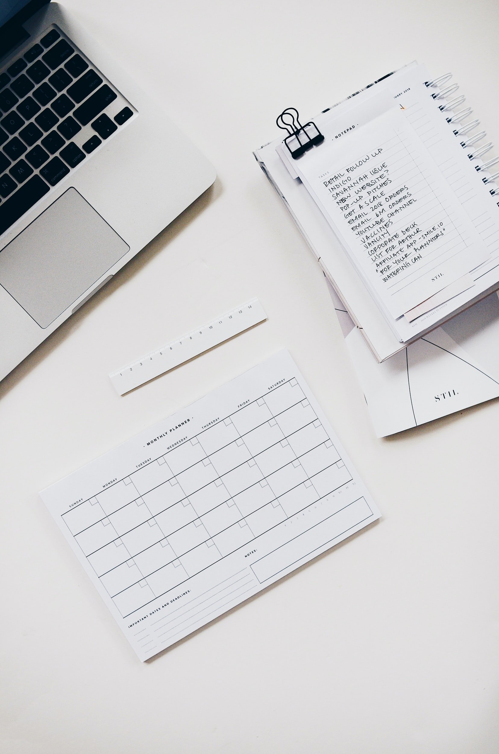 Photo by STIL on Unsplash A monthly planner, a ‘to do” list, and part of a laptop keyboard sit on a white table.