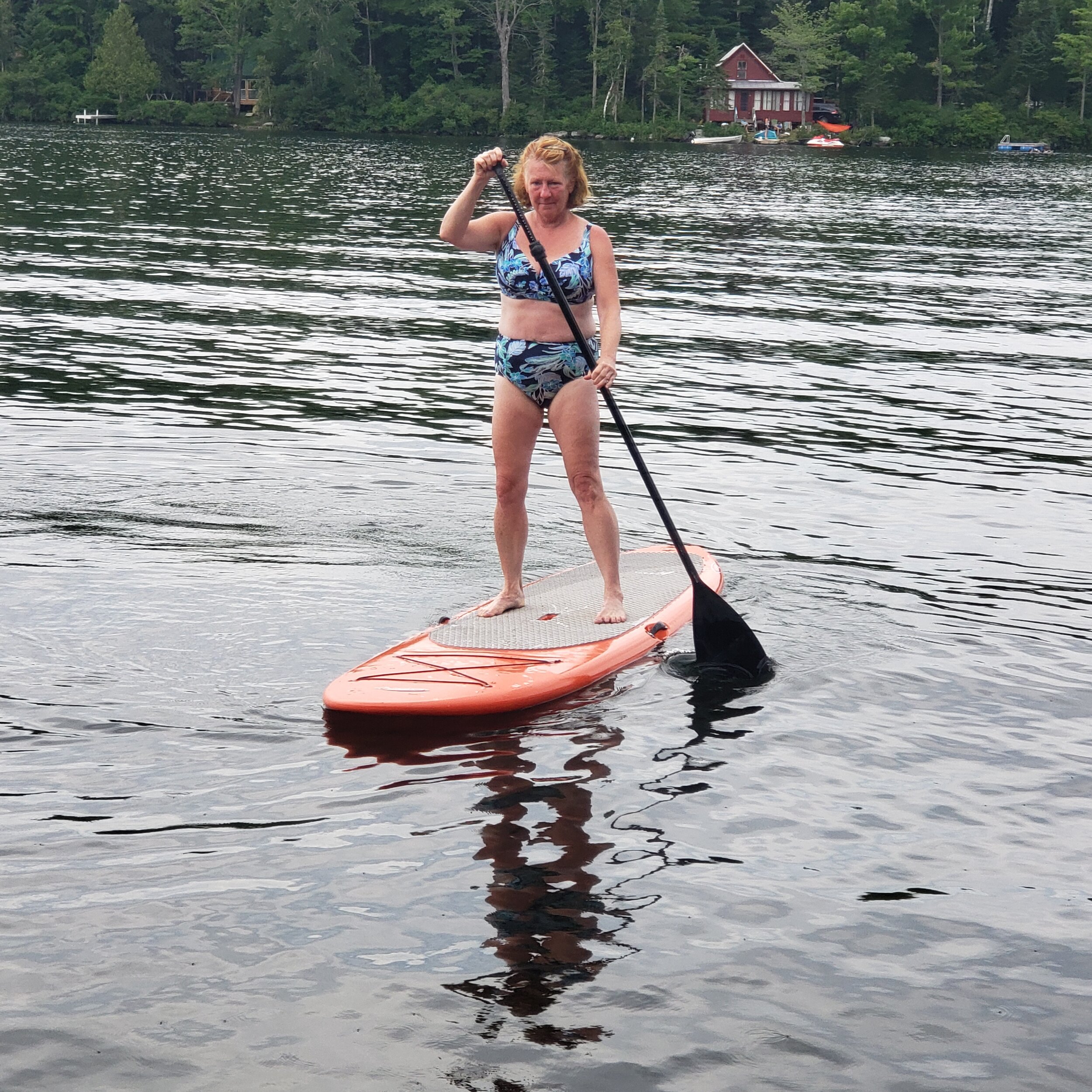 Photo of Annemarie paddle-boarding. She is wearing a blue swimsuit.