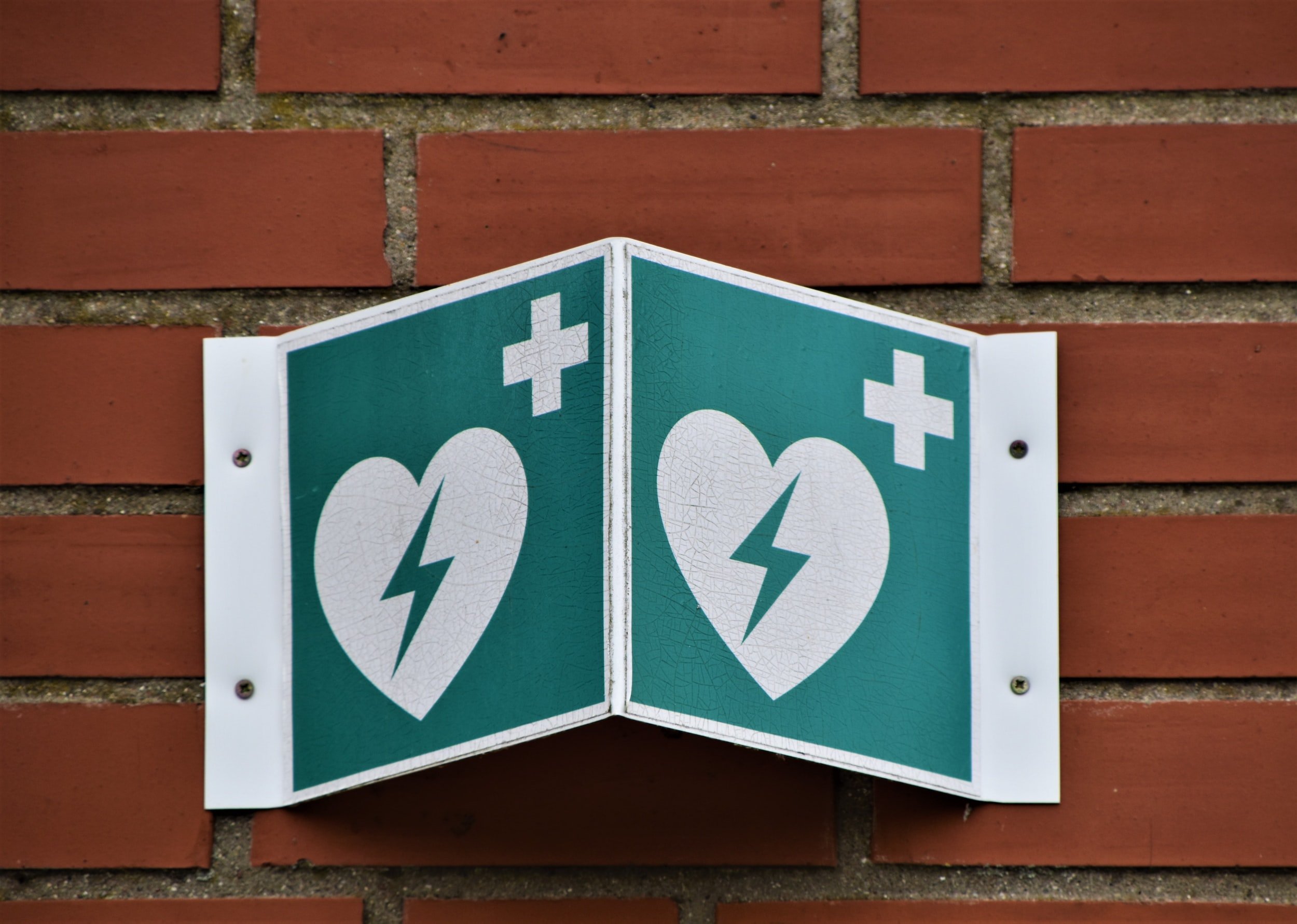 An AED Automated External Defibrillator sign. The sign is blue with a white heart that has a blue lightning bolt inside of it.