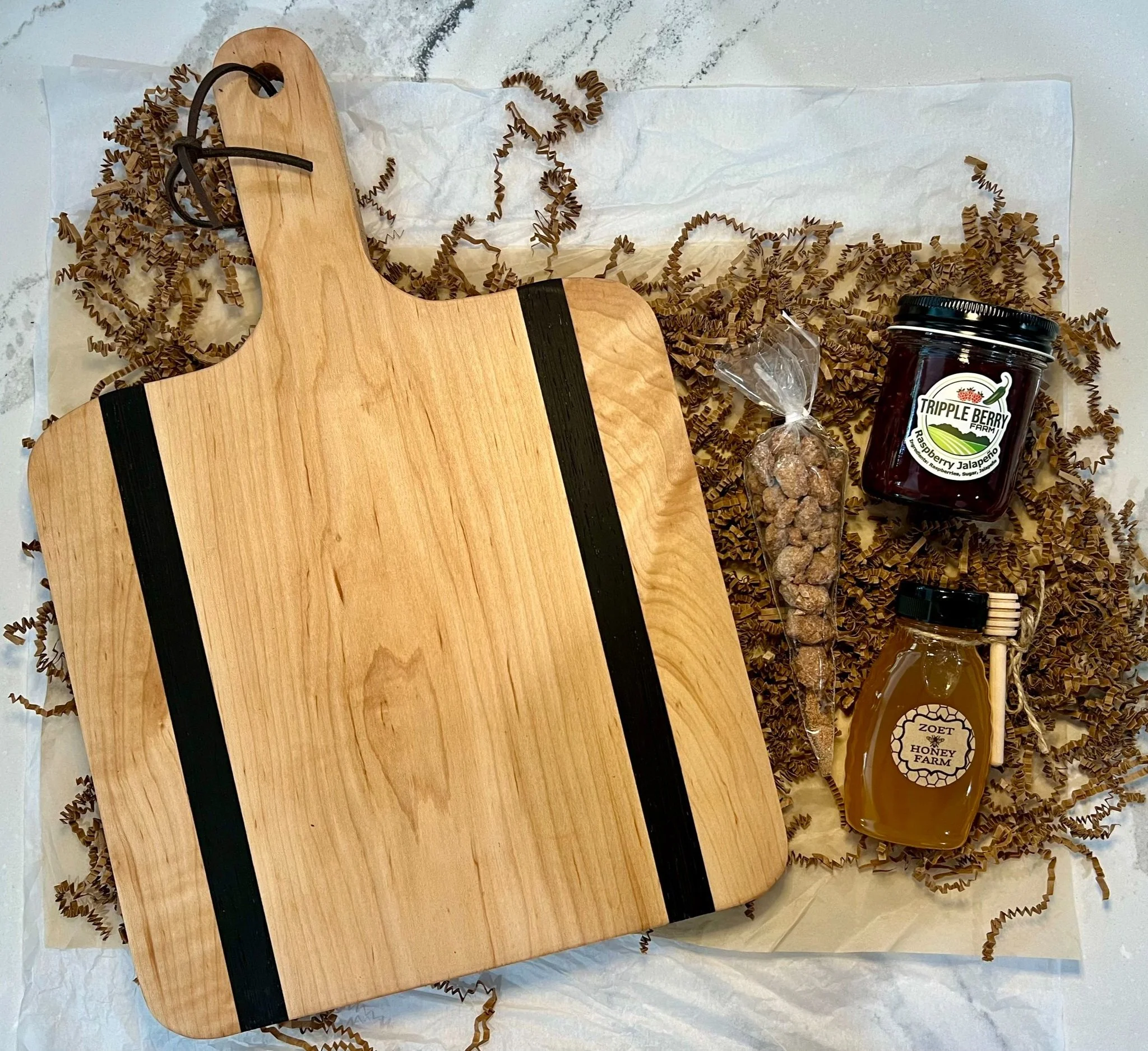 Charcuterie Holiday Box contents featuring: Large Handle Board, Zoet Farm Honey, Cinnamon Roasted Almonds, and Jalapeno Raspberry Jelly