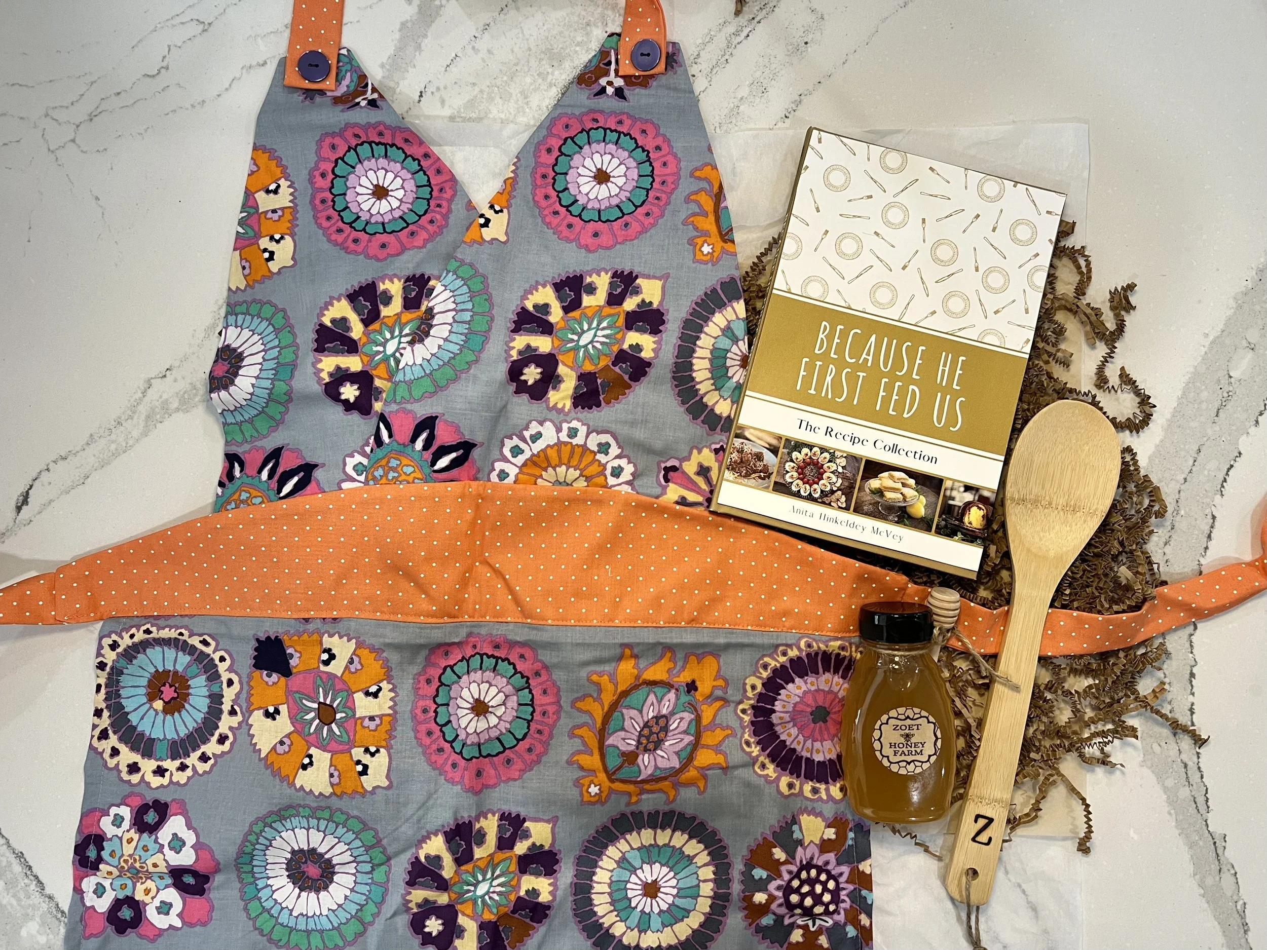 Chef's kiss holiday box featuring hand sewn apron, 8 oz Zoet Farm honey, Recipe Collection, and a monogrammed wooden spoon. All from local makers.