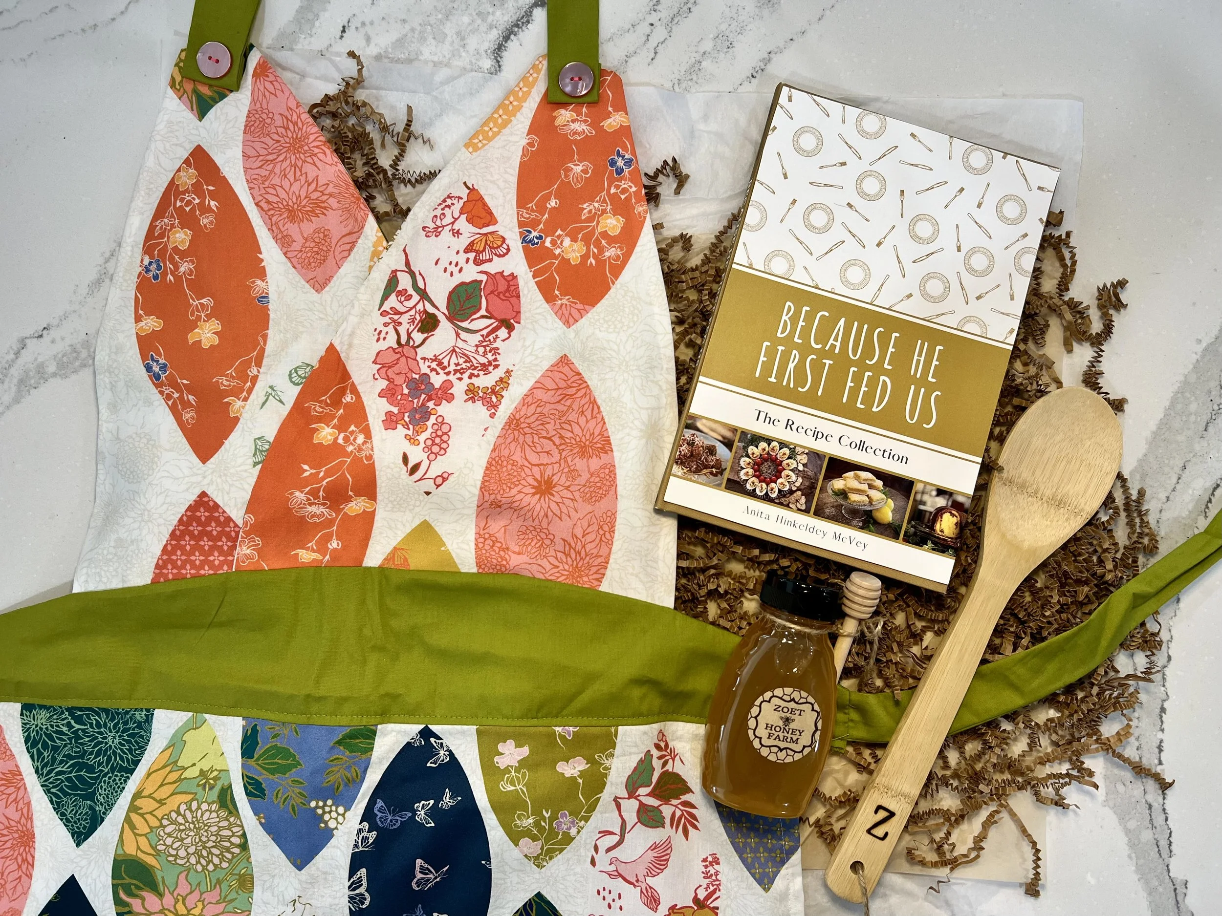 Chef's kiss holiday box featuring hand sewn apron, 8 oz Zoet Farm honey, Recipe Collection, and a monogrammed wooden spoon. All from local makers.