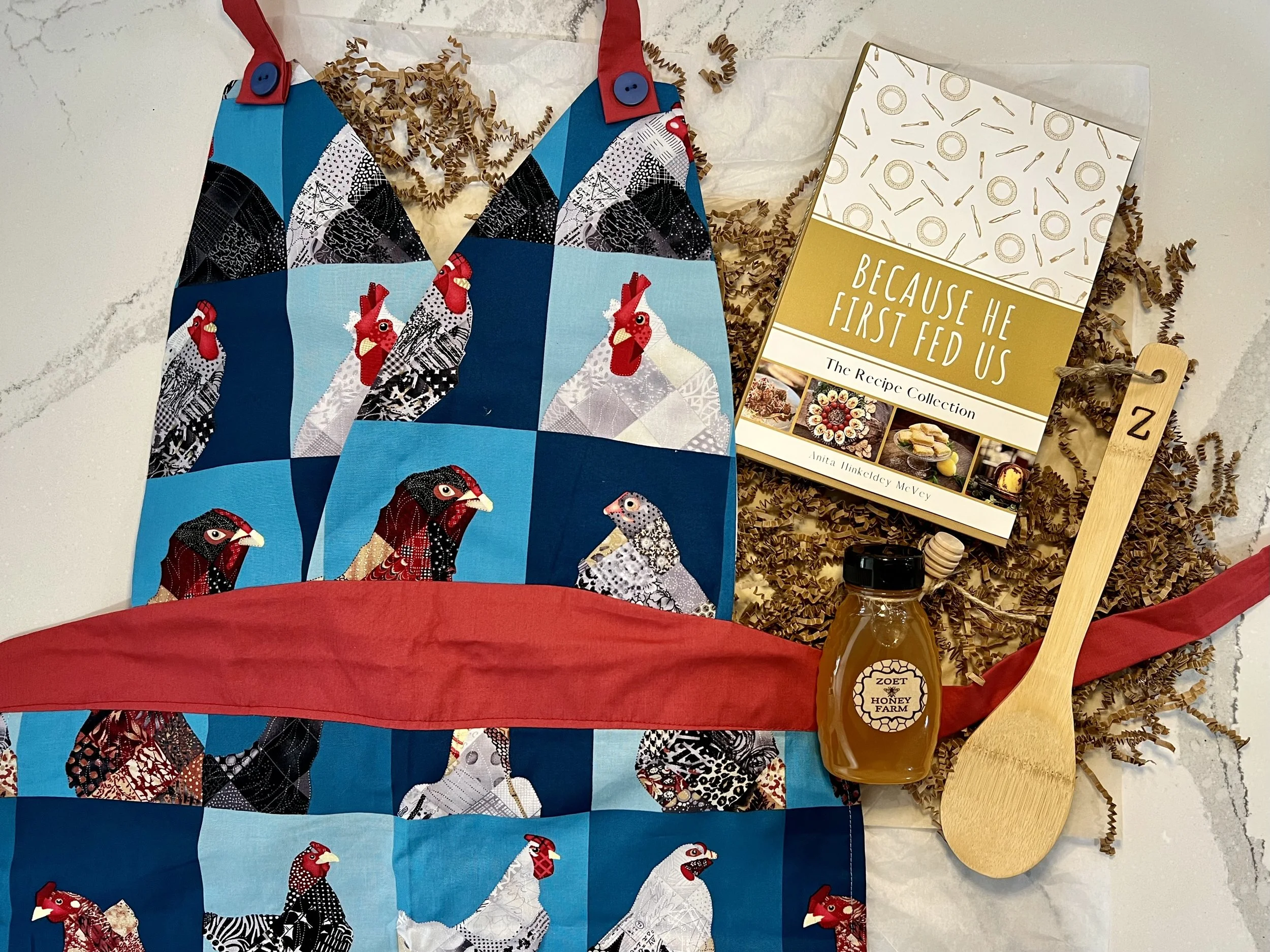 Chef's kiss holiday box featuring hand sewn apron, 8 oz Zoet Farm honey, Recipe Collection, and a monogrammed wooden spoon. All from local makers.