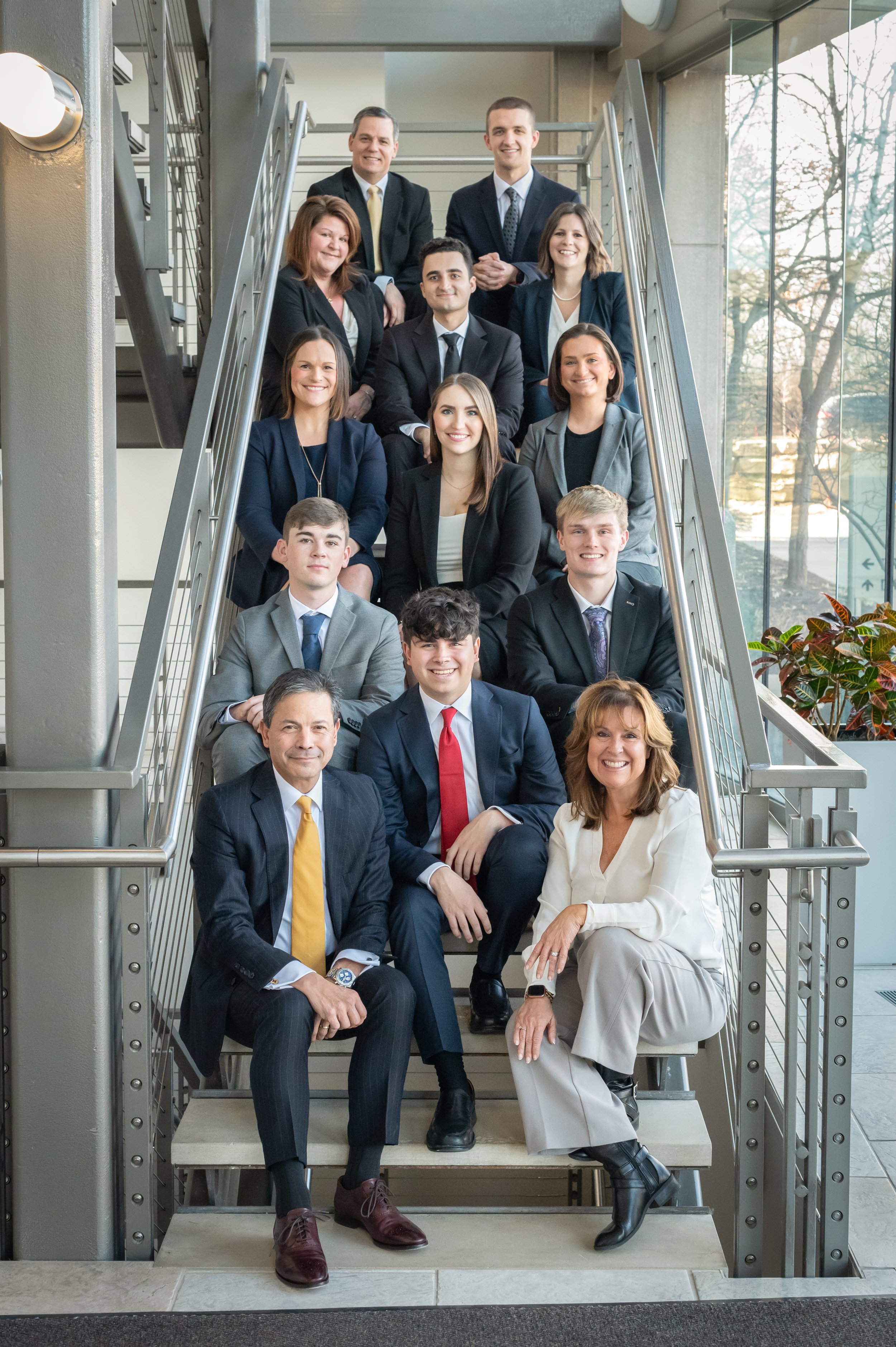 Group of professionally dressed people sitting on staircase in office building.