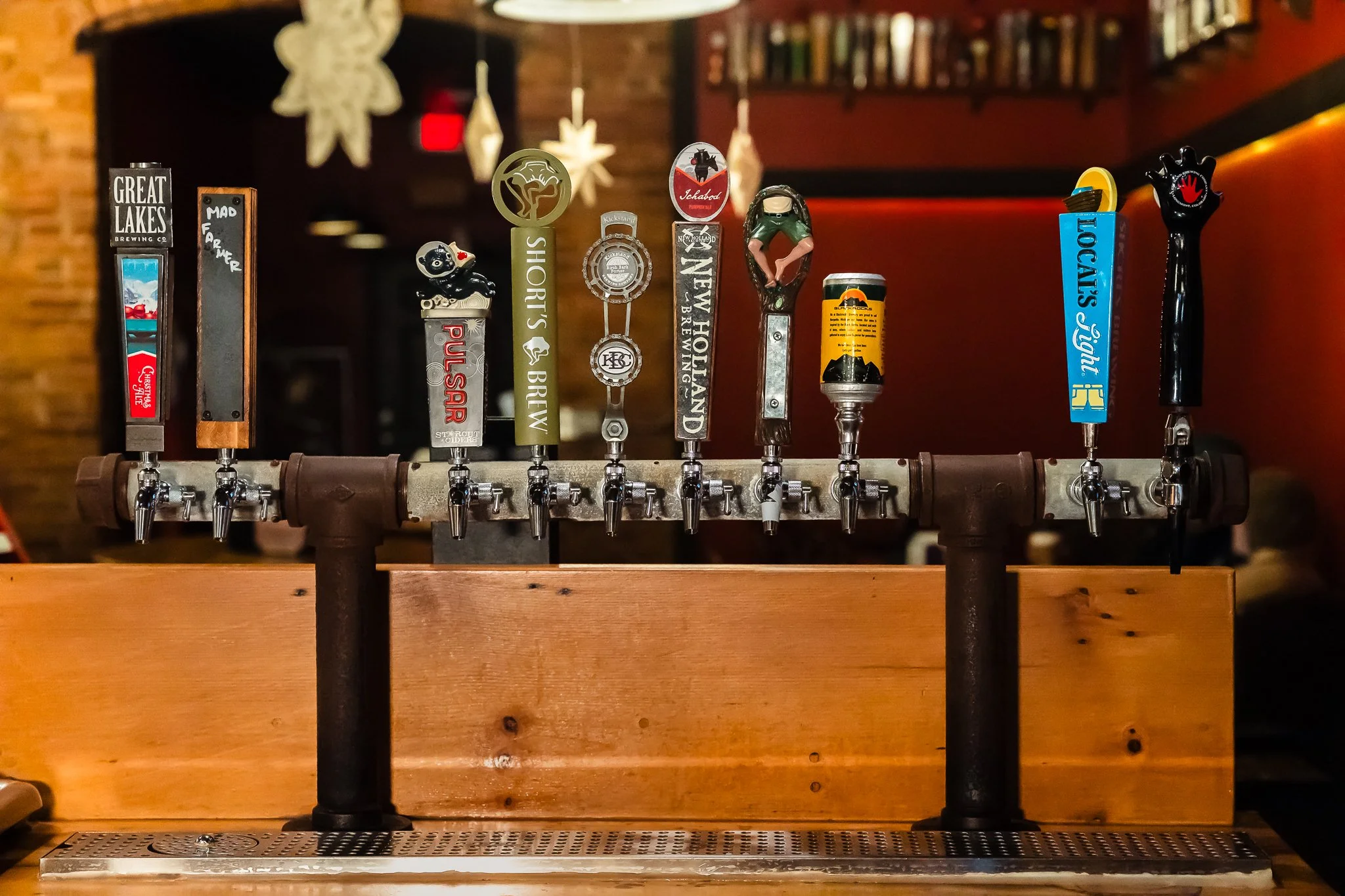 A row of beer taps on a bar counter, each with different decorative handles representing different breweries and beers.