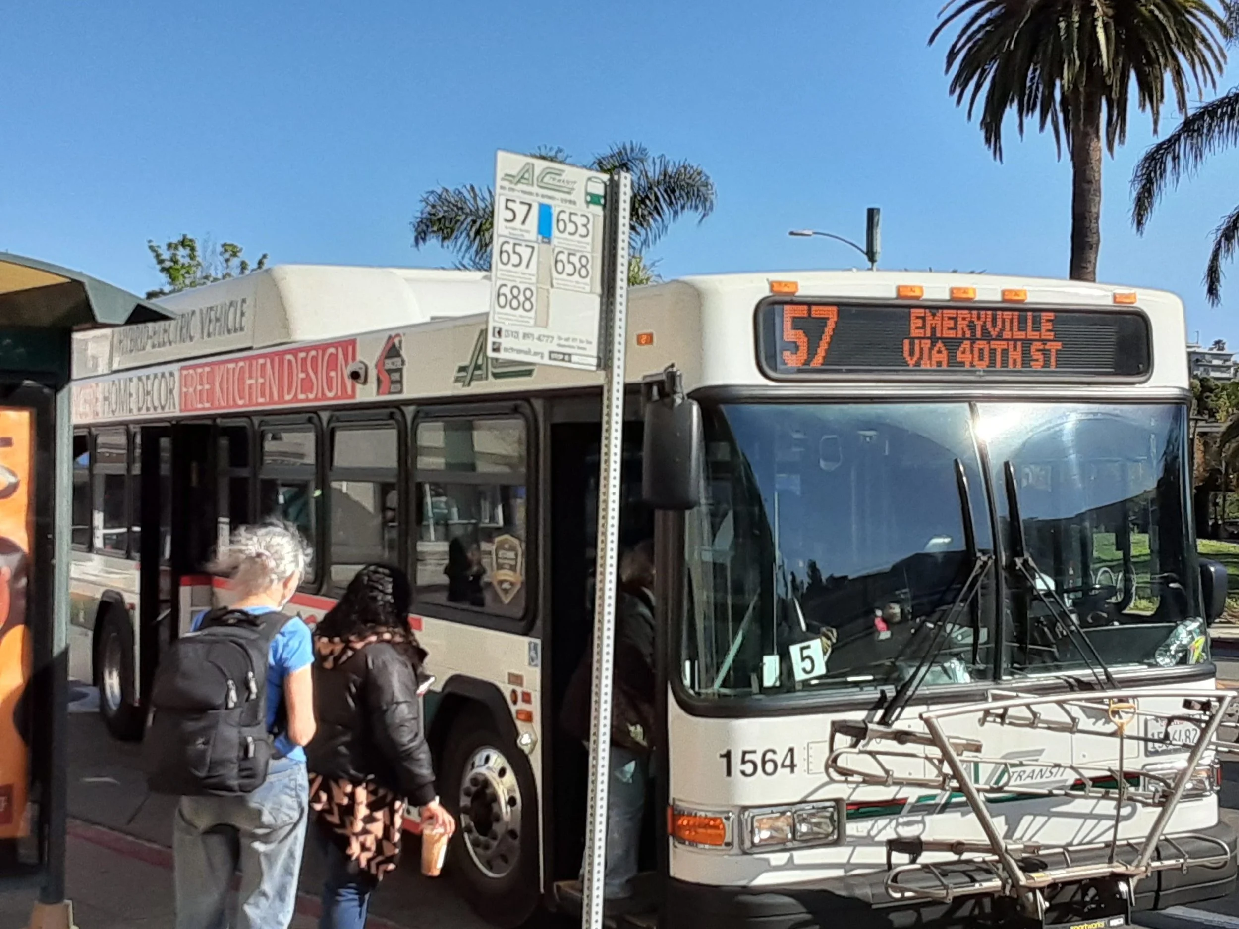 Riders wait at at an AC Transit bus stop waiting to get on the 57 bus as it pulls up.