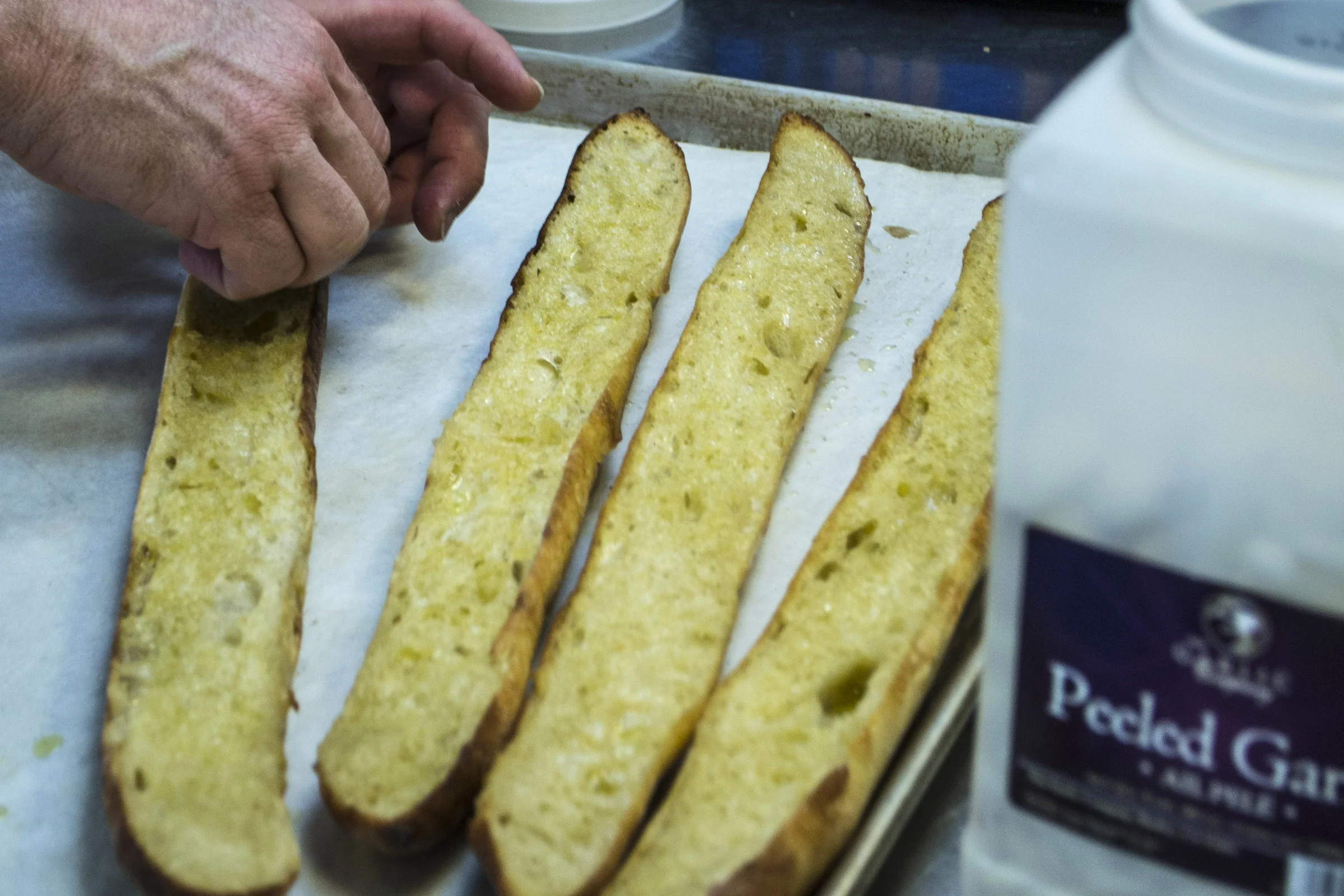 Rustic Italian Garlic Bread made by toasting Old Dog Baking Co. baguettes with olive oil and finishing off by rubbing with fresh garlic.