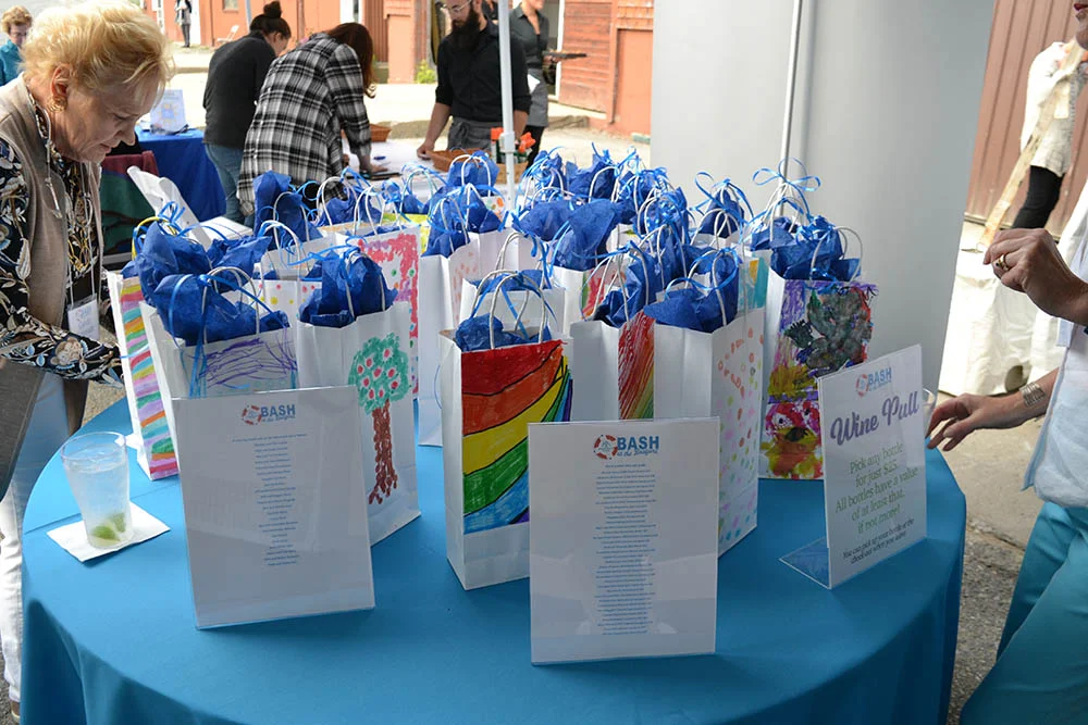 Colorful bags were created by summer campers and used to keep each bottle of wine a “mystery”