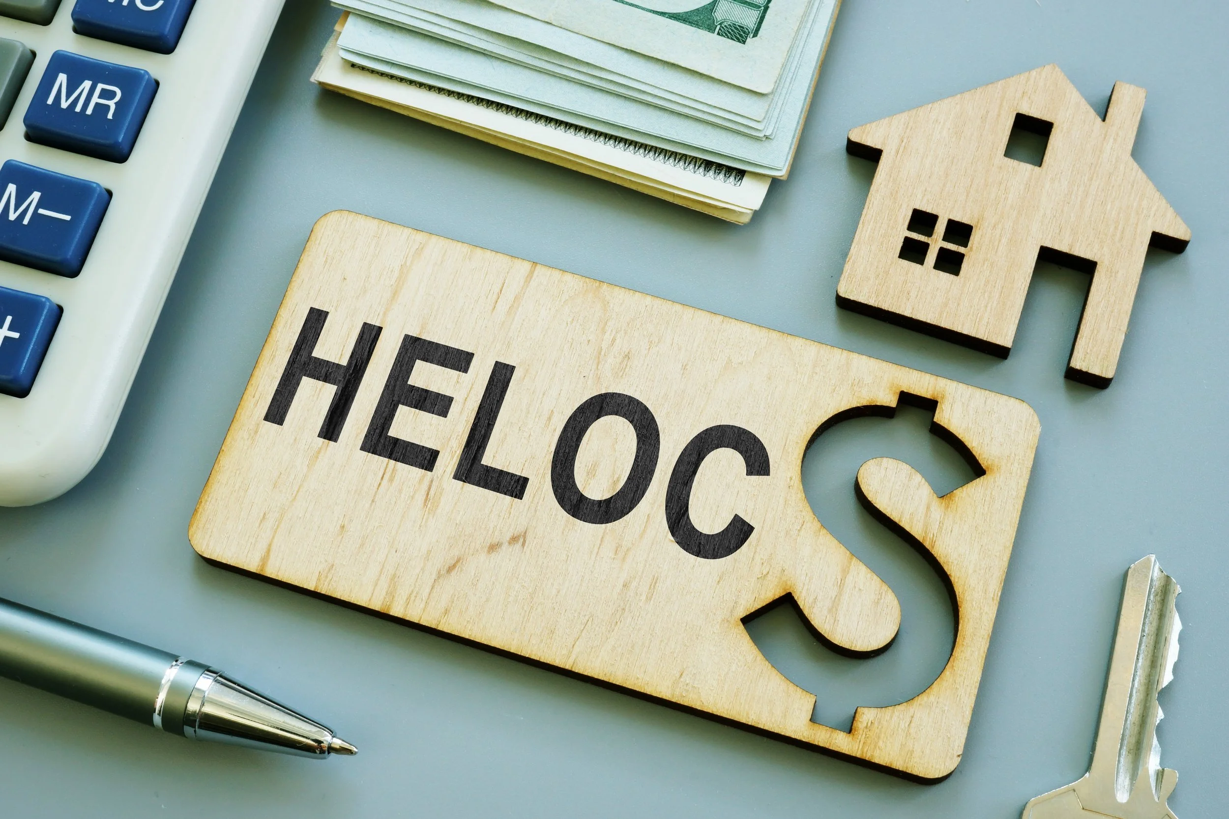 HELOCs sign with calculator, money, calculator and pen in the view