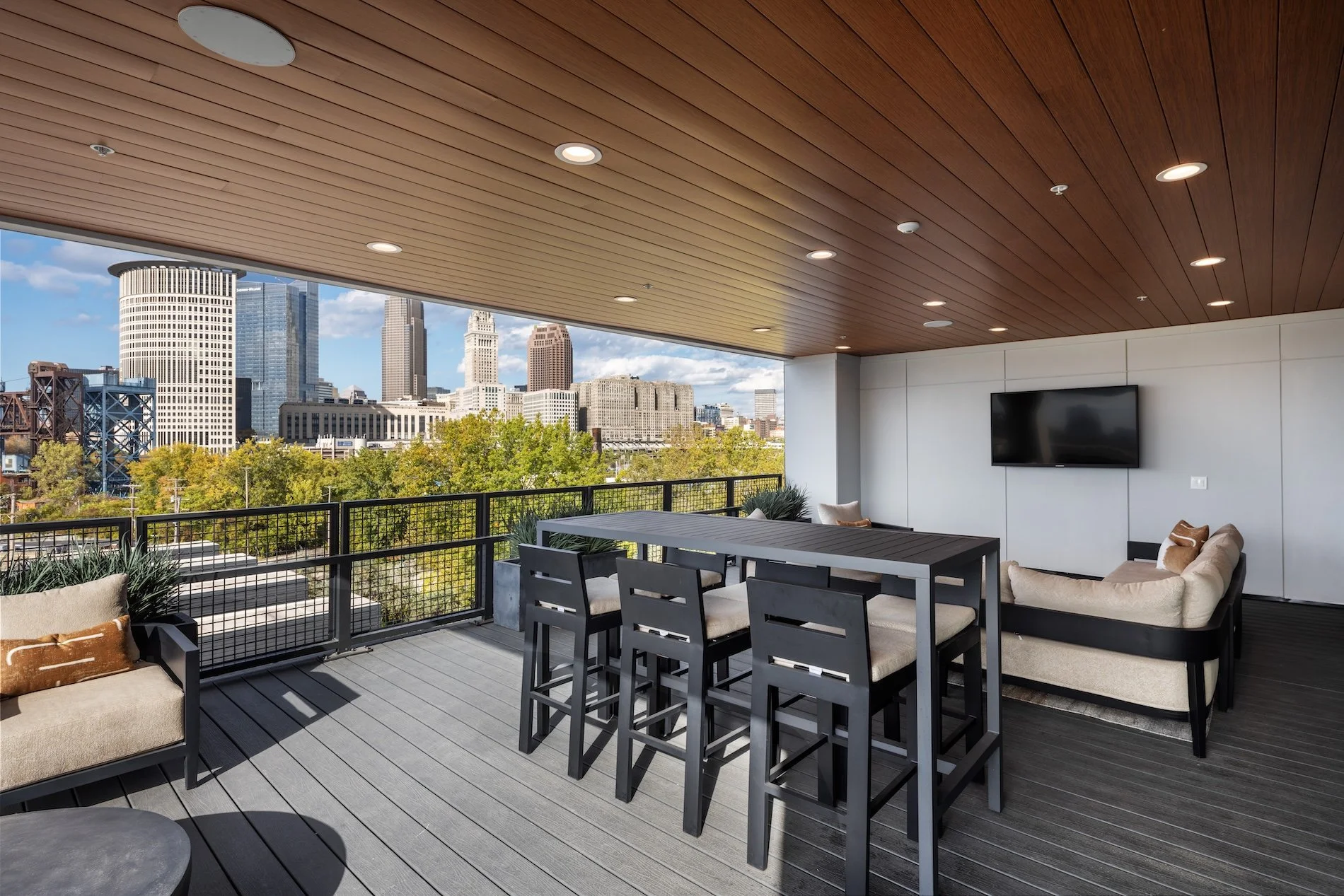 Covered rooftop lounge at The Collins residential community in Cleveland, featuring outdoor seating, dining space, and panoramic views of the downtown skyline.