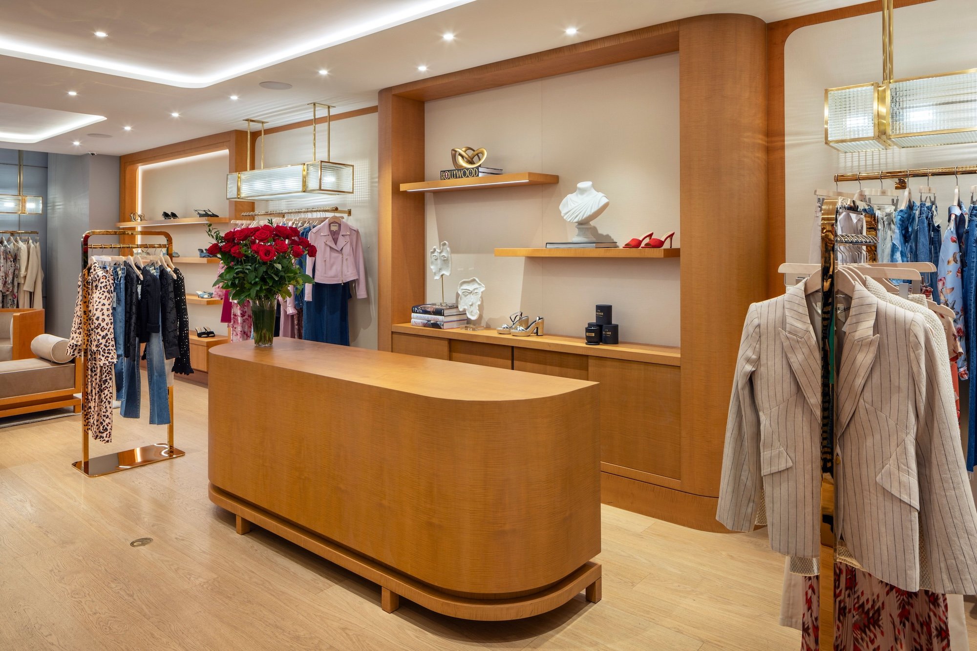 Warm interior of the L'AGENCE flagship boutique in New York City, featuring custom wood millwork, brass clothing displays, curated merchandise, and residential-inspired retail design by Paul Bennett Architects.