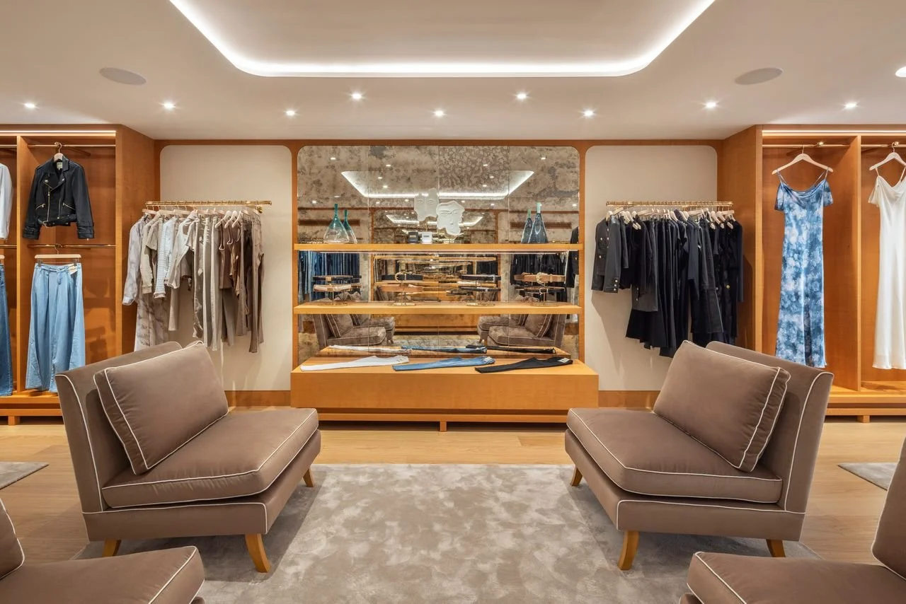 Warm residential-style lounge within the L'AGENCE flagship boutique, showcasing custom millwork, curated displays, and hospitality-inspired retail design by Paul Bennett Architects.