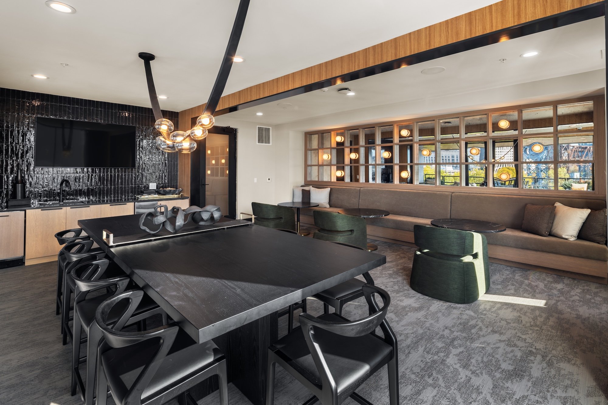 Shared amenity lounge at The Collins residential development, showcasing contemporary furnishings, custom lighting, textured materials, and connected indoor-outdoor gathering spaces.