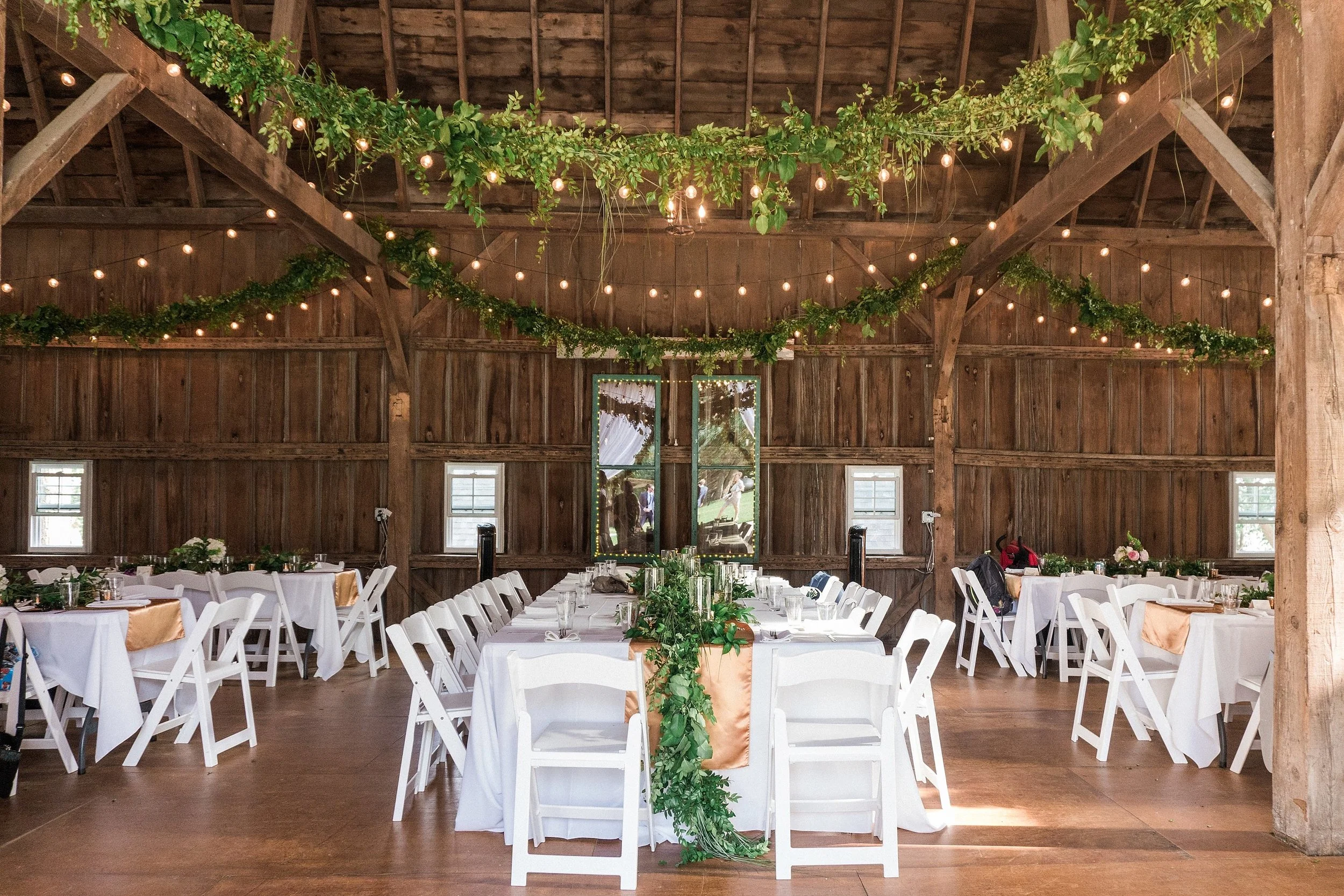 garland and cafe lights strung from beams of a barn