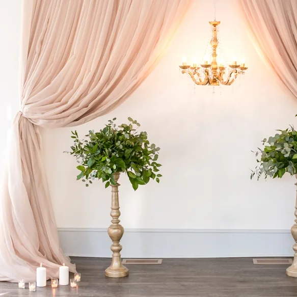 taupe curtain backdrop tied back with gold chandelier and candlesticks