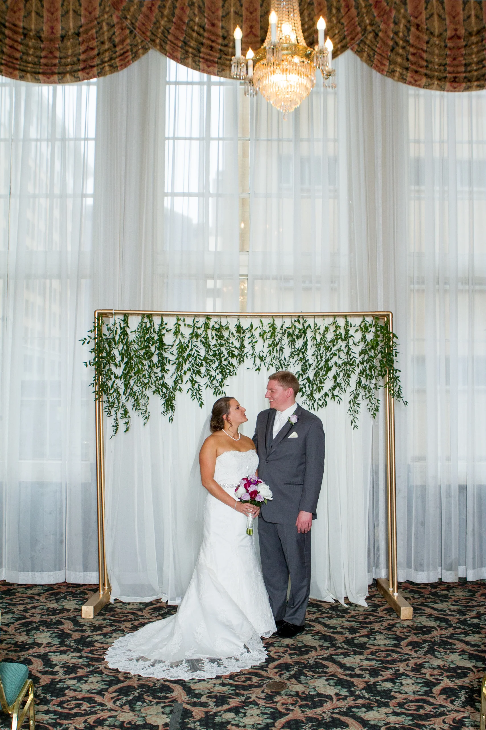 white curtain backdrop with gold pipes and added greenery