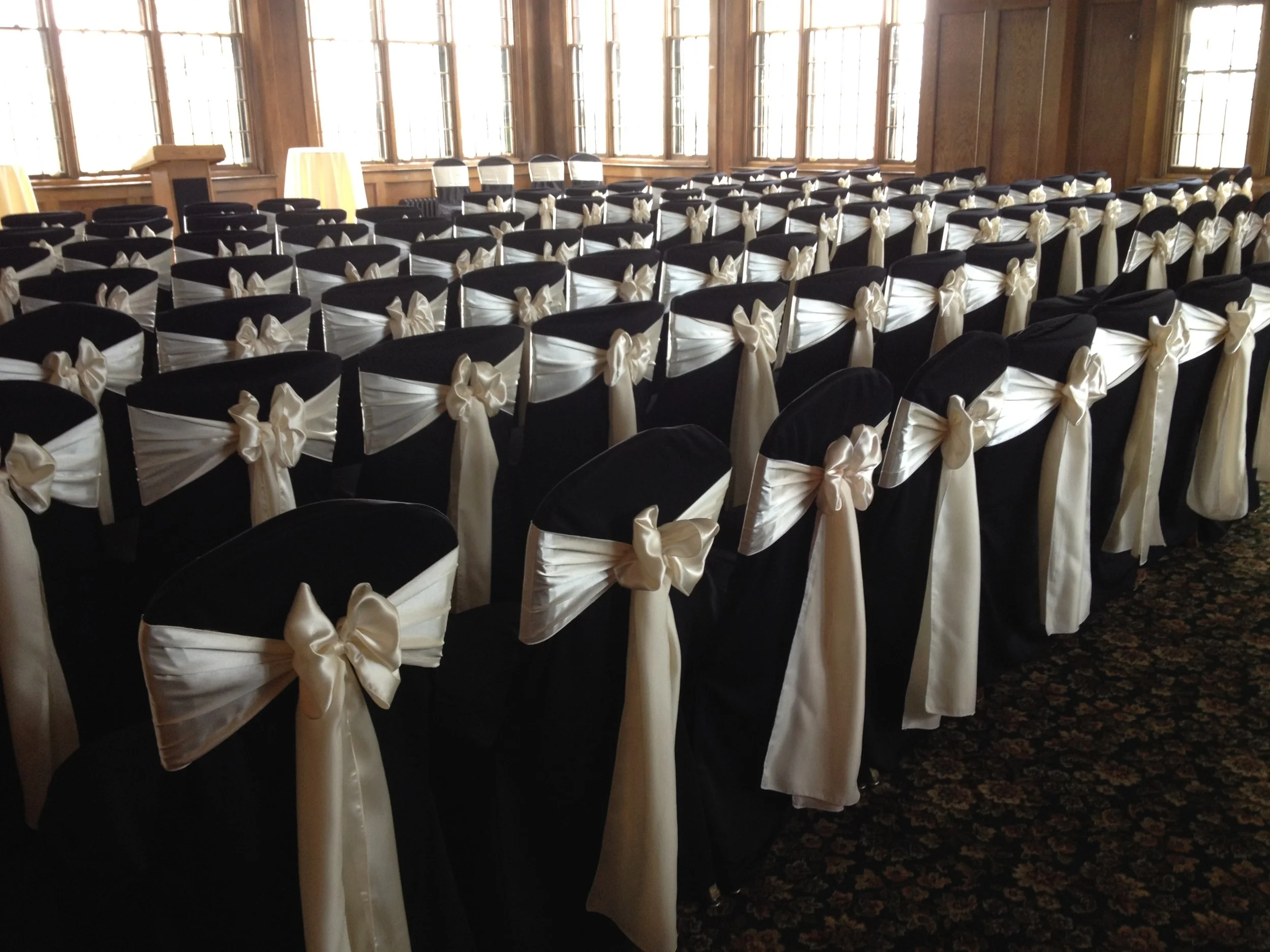 ivory satin sashes on chairs lined for wedding ceremony