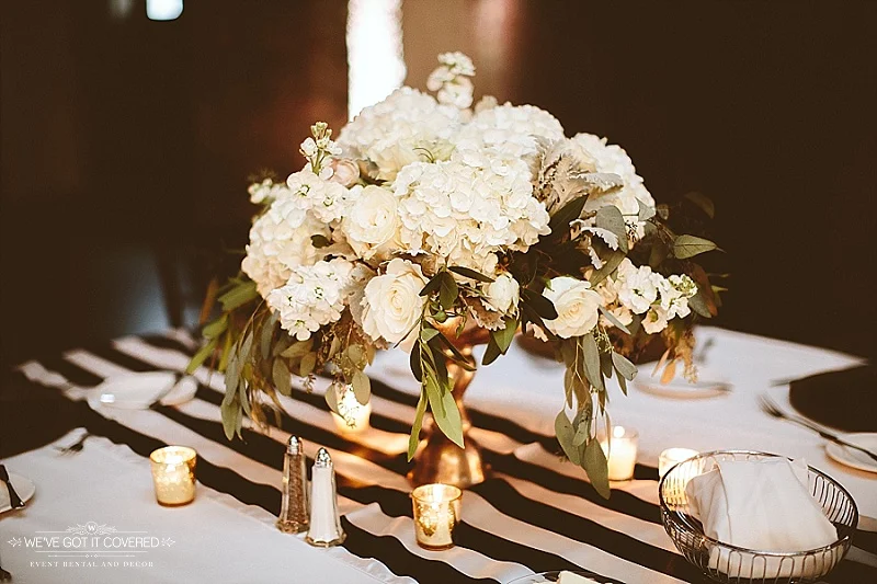 Table decor including flowers, candles and a back and white stripe table runner.